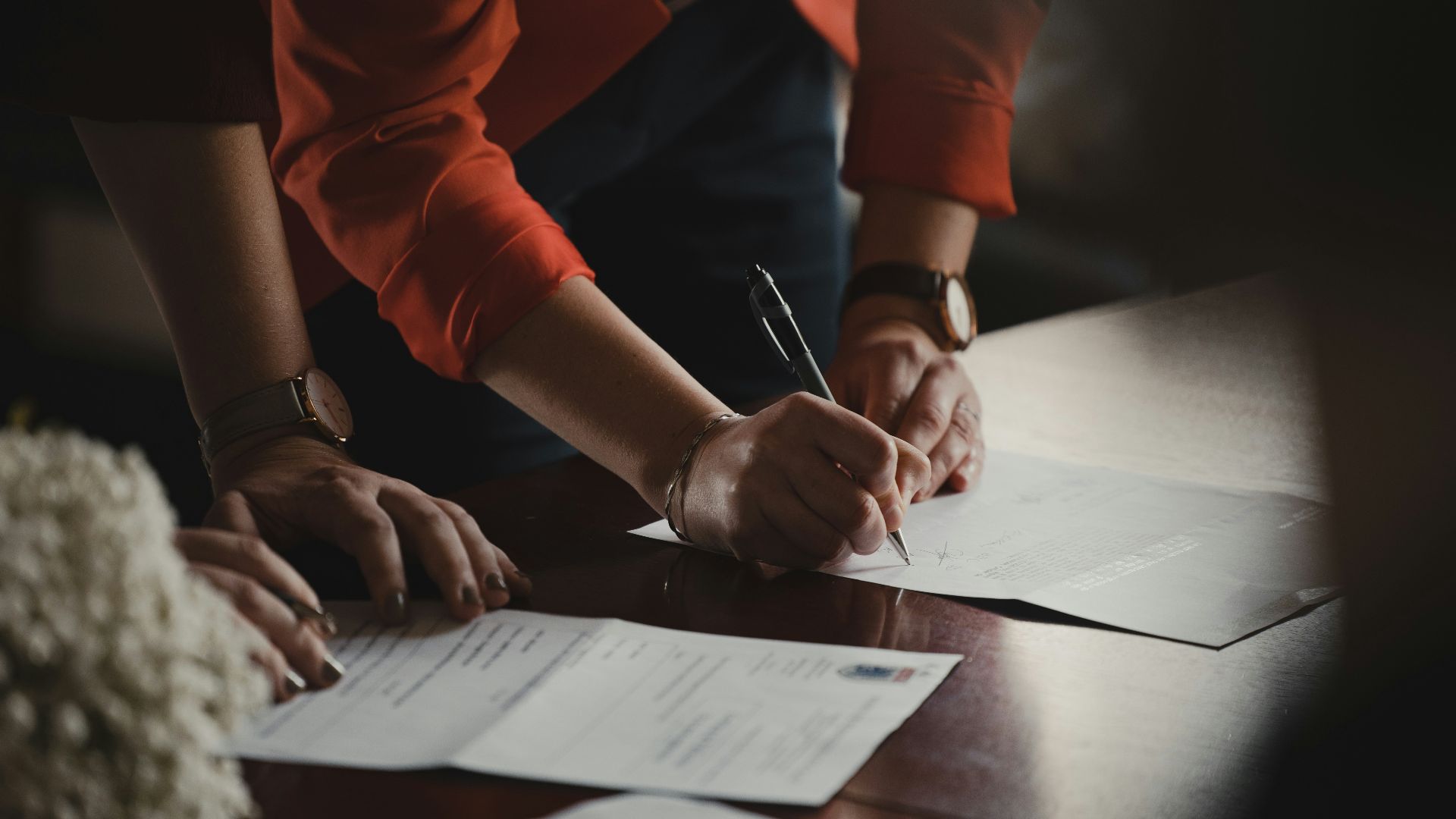 person in orange long sleeve shirt writing on white paper