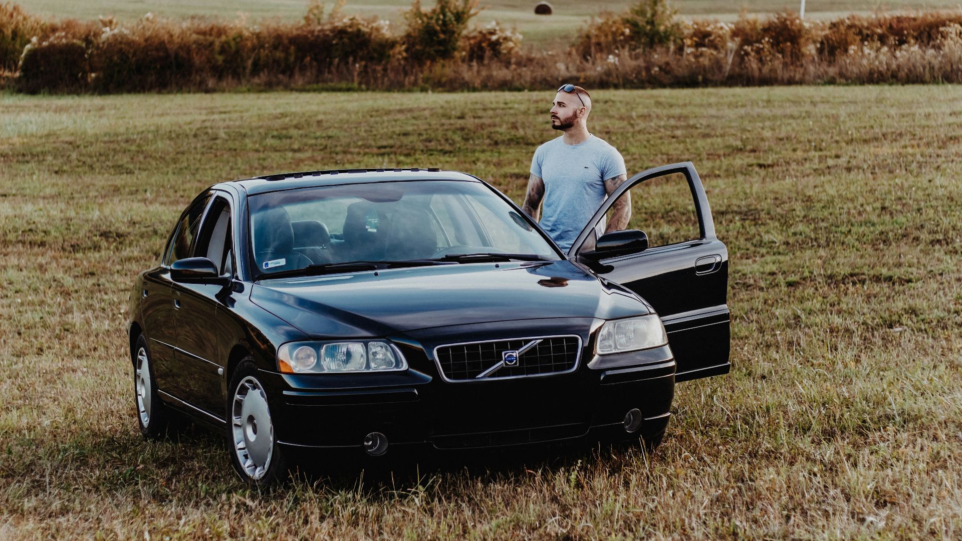 man standing beside black Volve S40 vehicle at daytime
