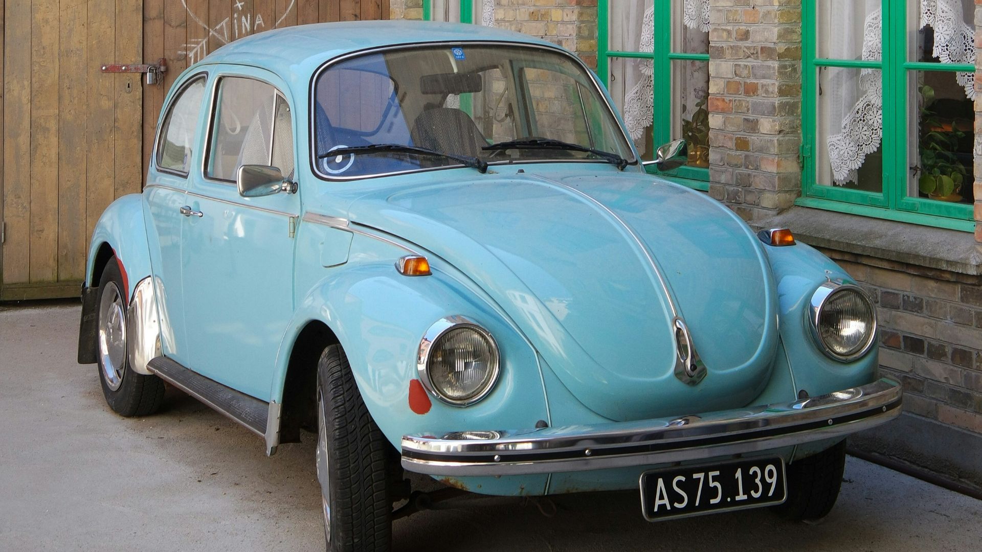 parked teal Volkswagen Beetle coupe beside wall