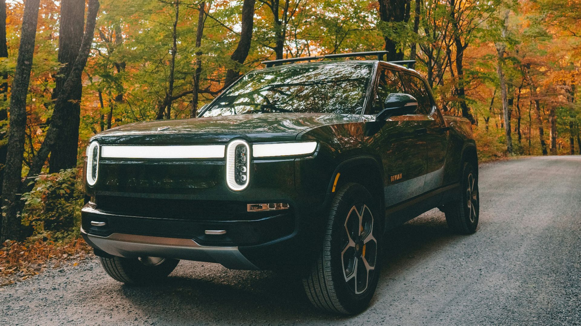 a black car parked on a road surrounded by trees