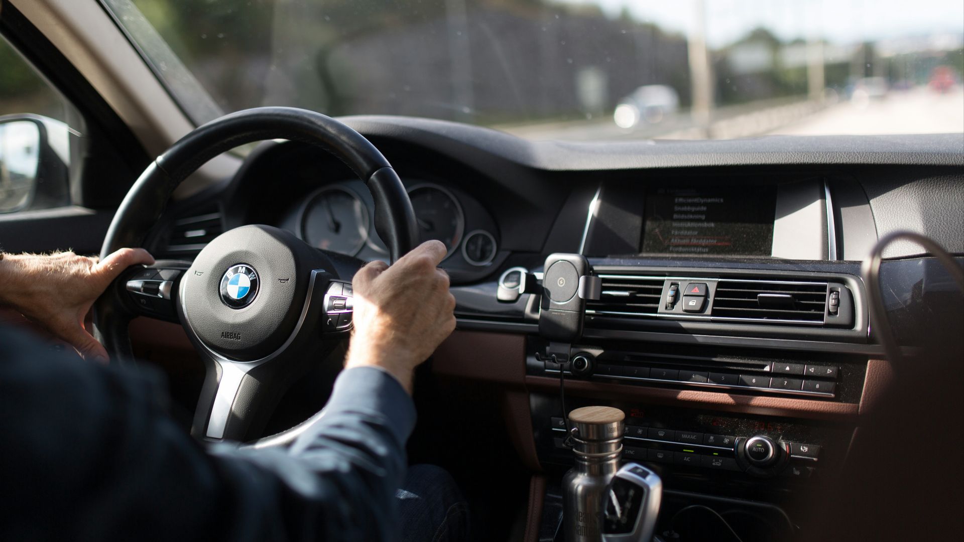 person holding BMW steering wheel