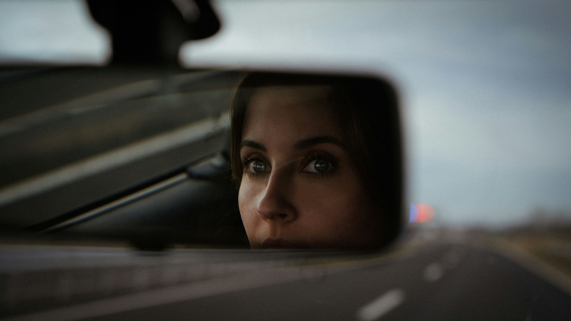a woman's reflection in the side view mirror of a car