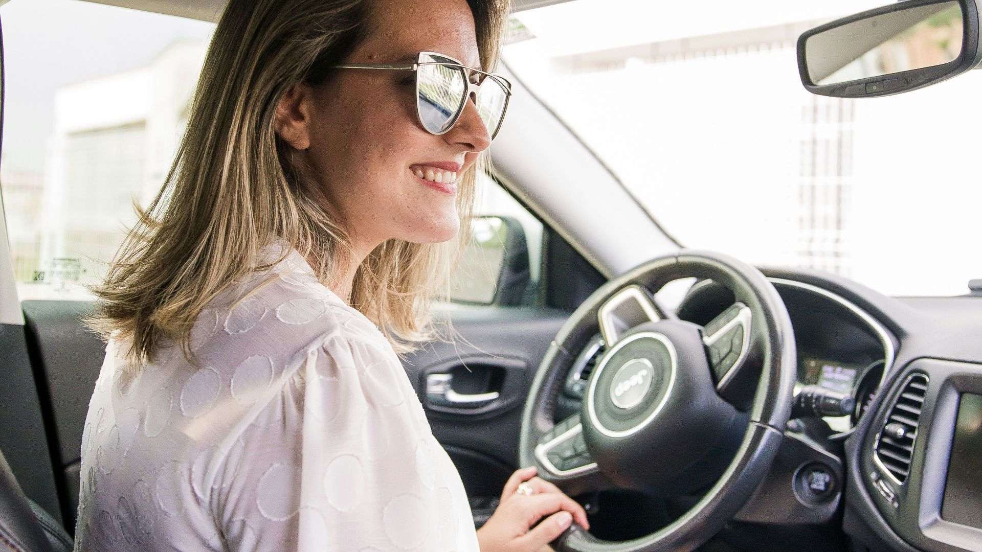 woman in white long sleeve shirt driving car
