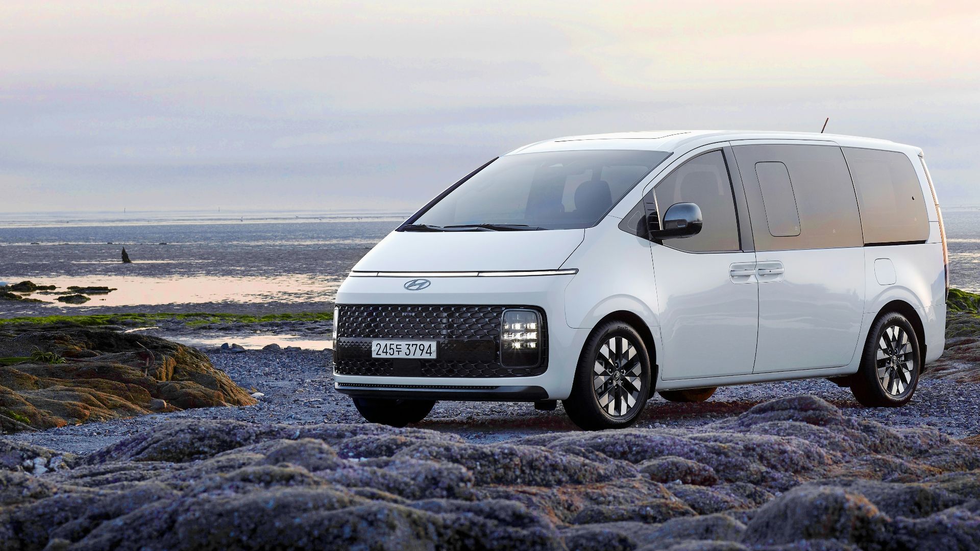 a white van parked on top of a rocky beach