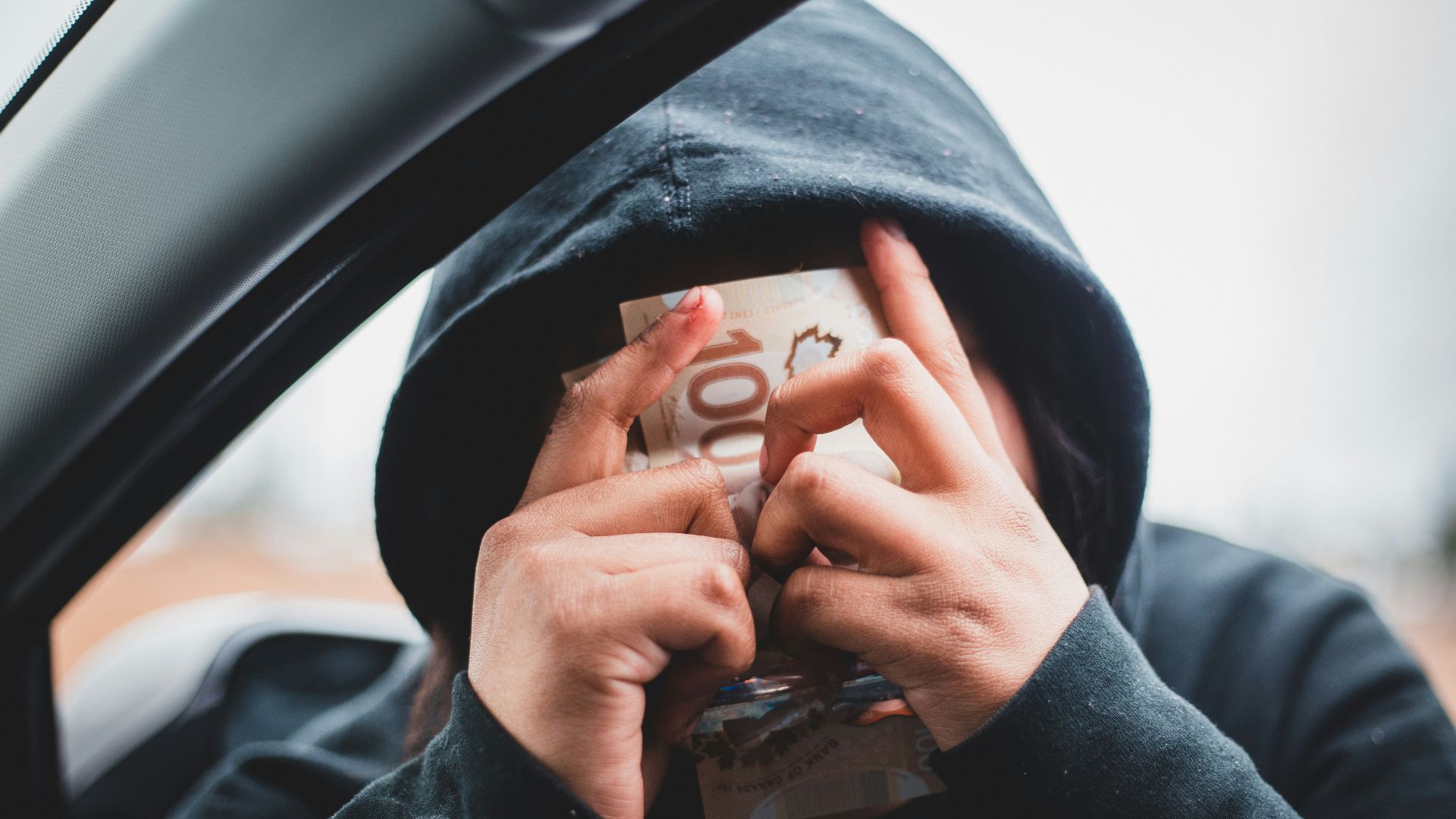a person in a hoodie holding a book in their hands