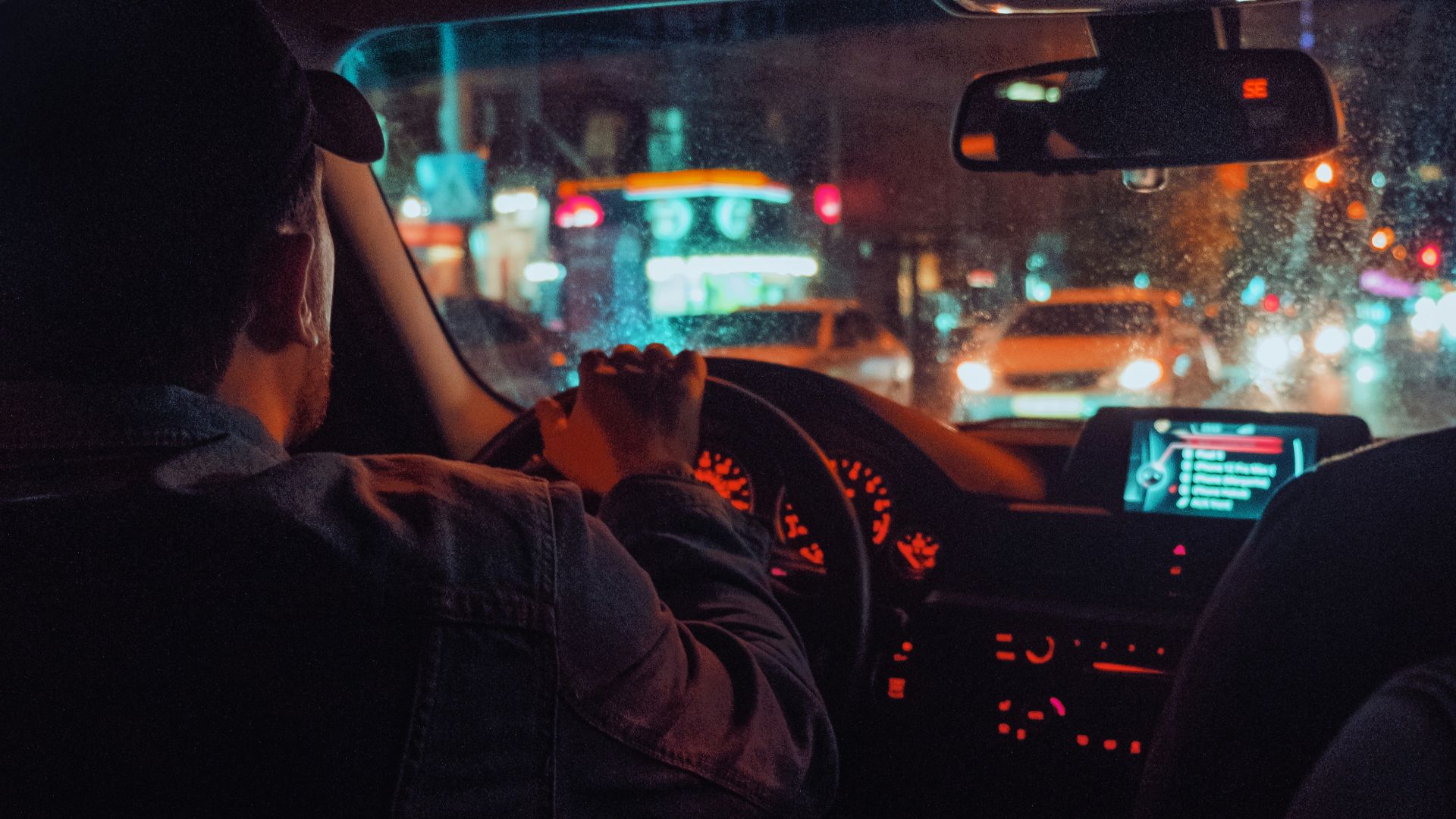 a man driving a car at night in the city