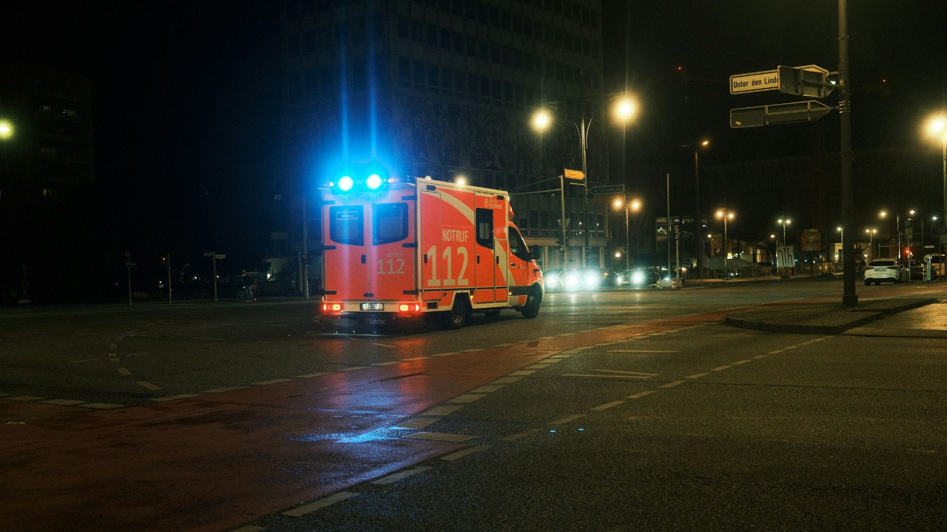 a large red truck driving down a street at night