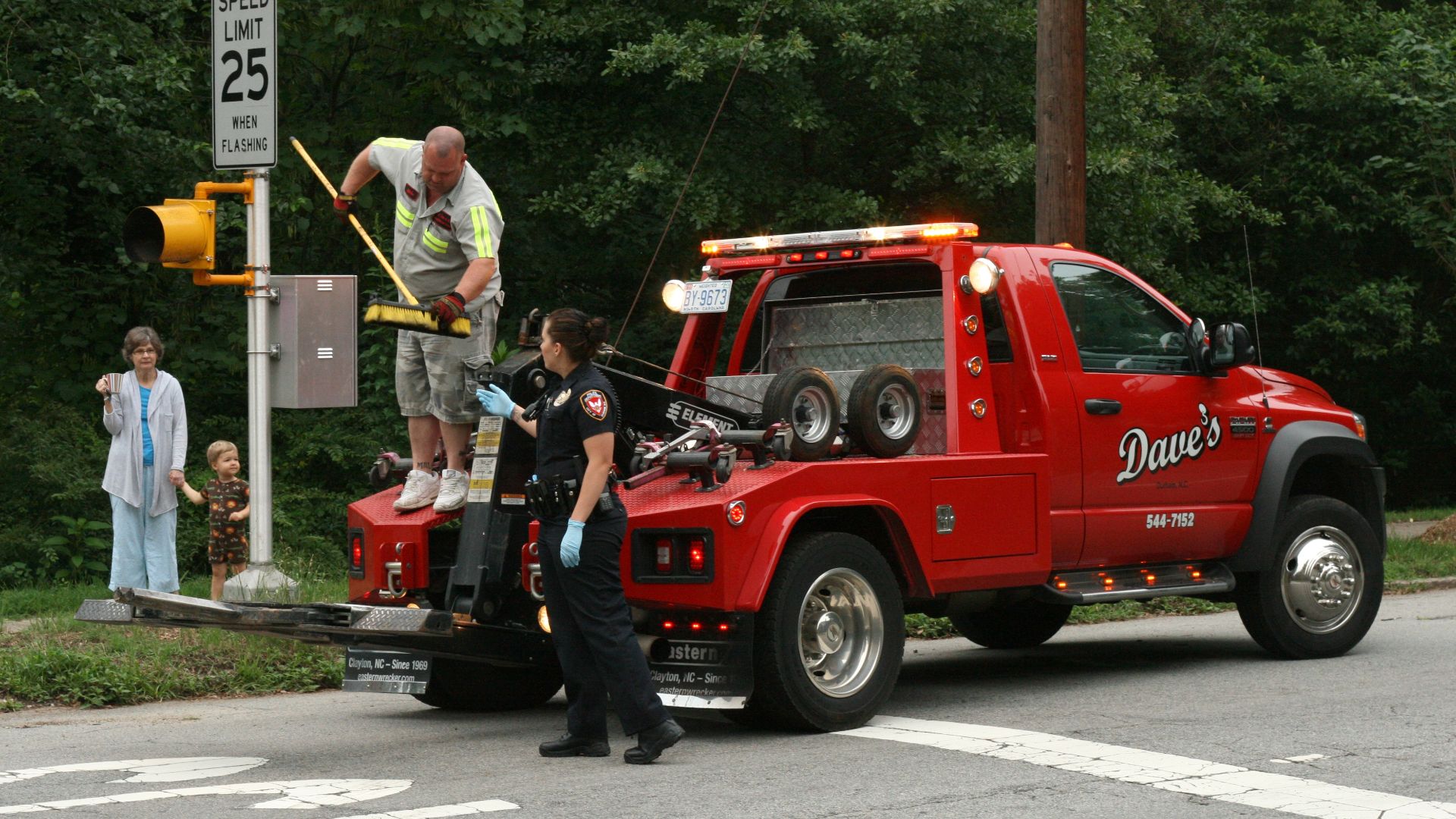 File:2010-05-30 Tow truck driver hands broom to officer.jpg
