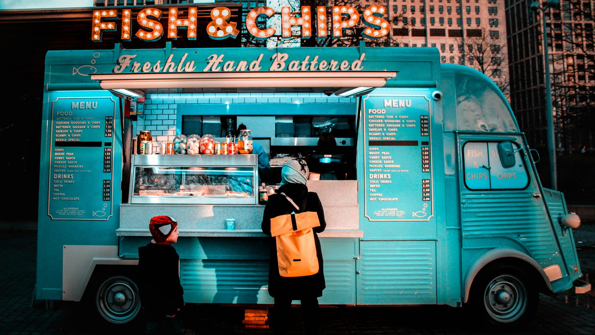 woman in brown coat standing in front of food stall