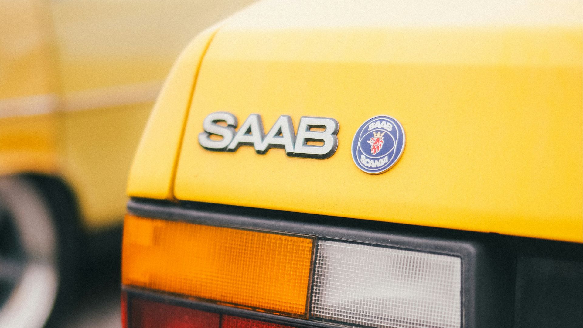 the rear end of a yellow saab car