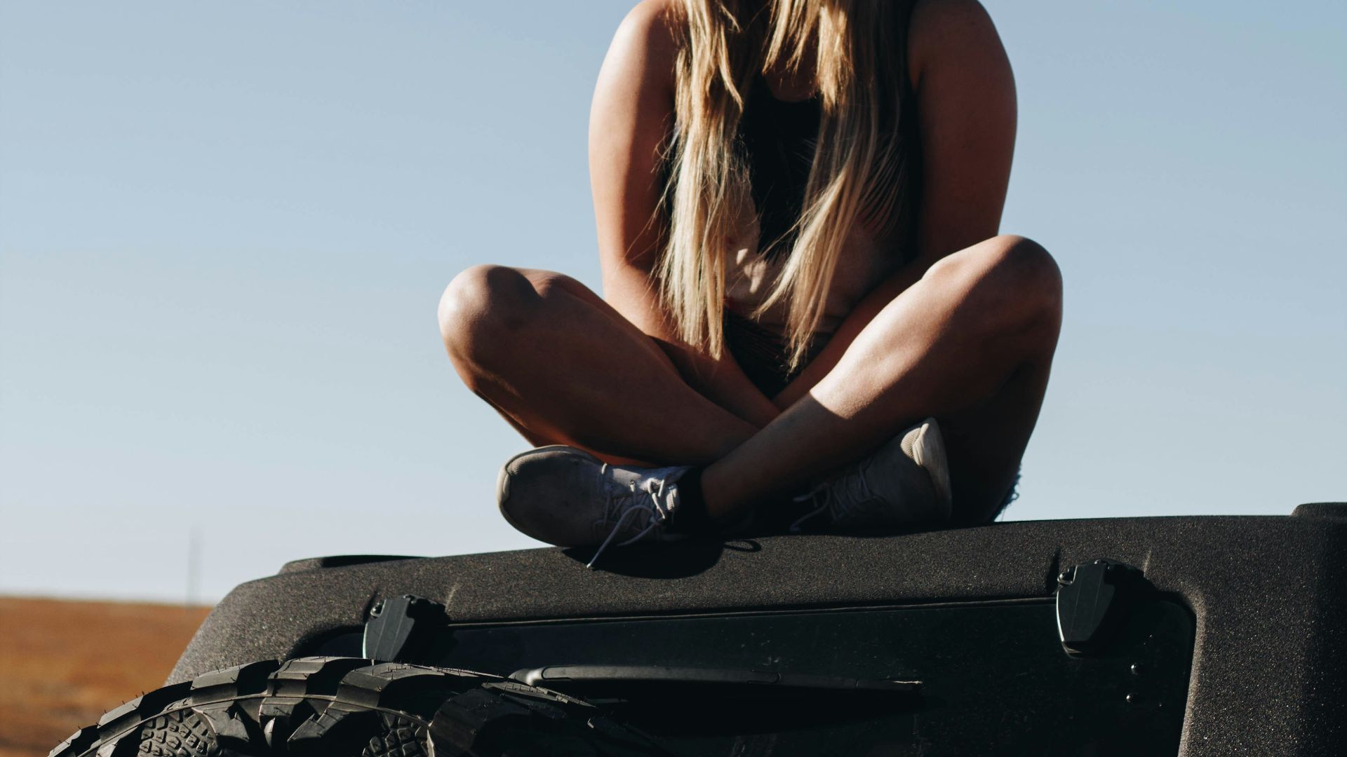 woman sitting above car roof
