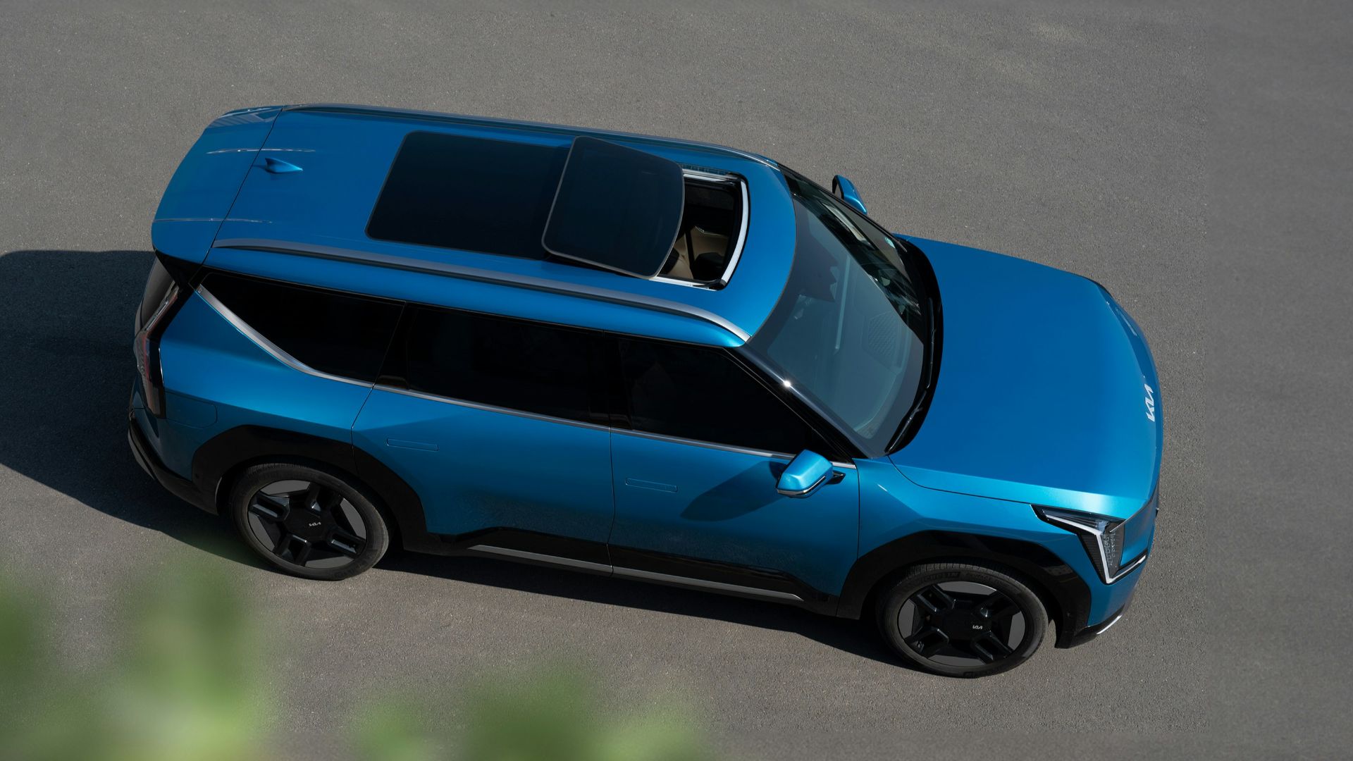 a blue car driving down a road next to a forest