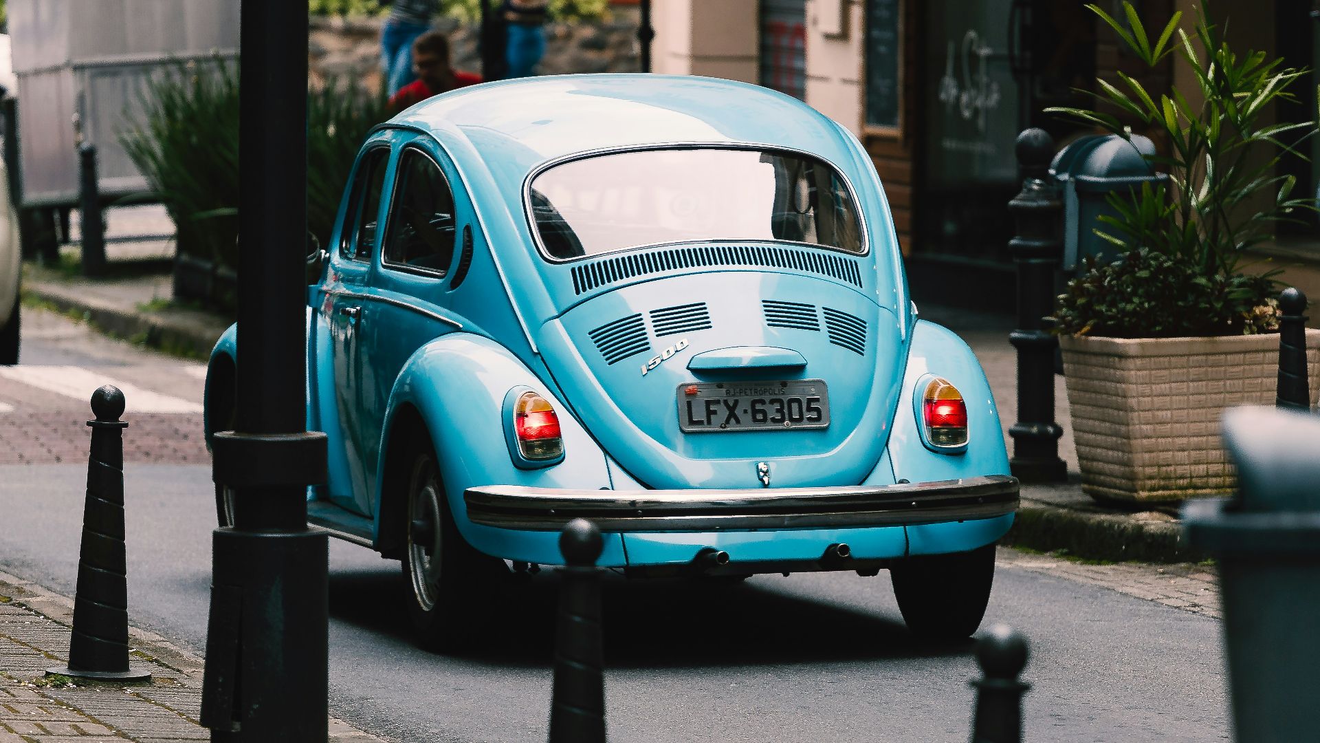 teal volkswagen beetle parked on sidewalk during daytime