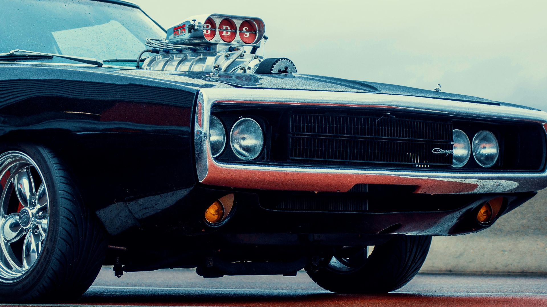a black muscle car with chrome rims parked on the street