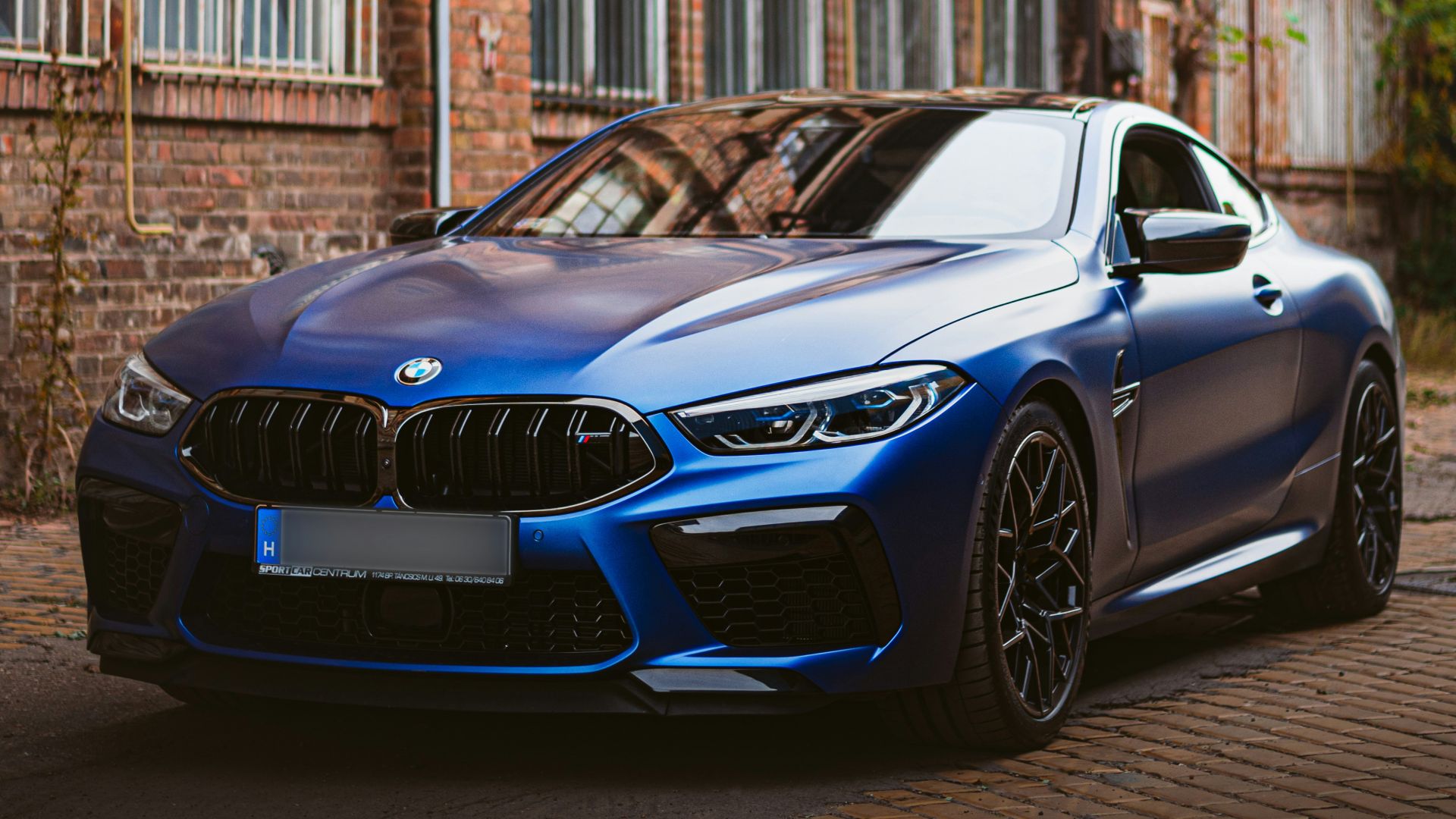 a blue car parked in front of a brick building