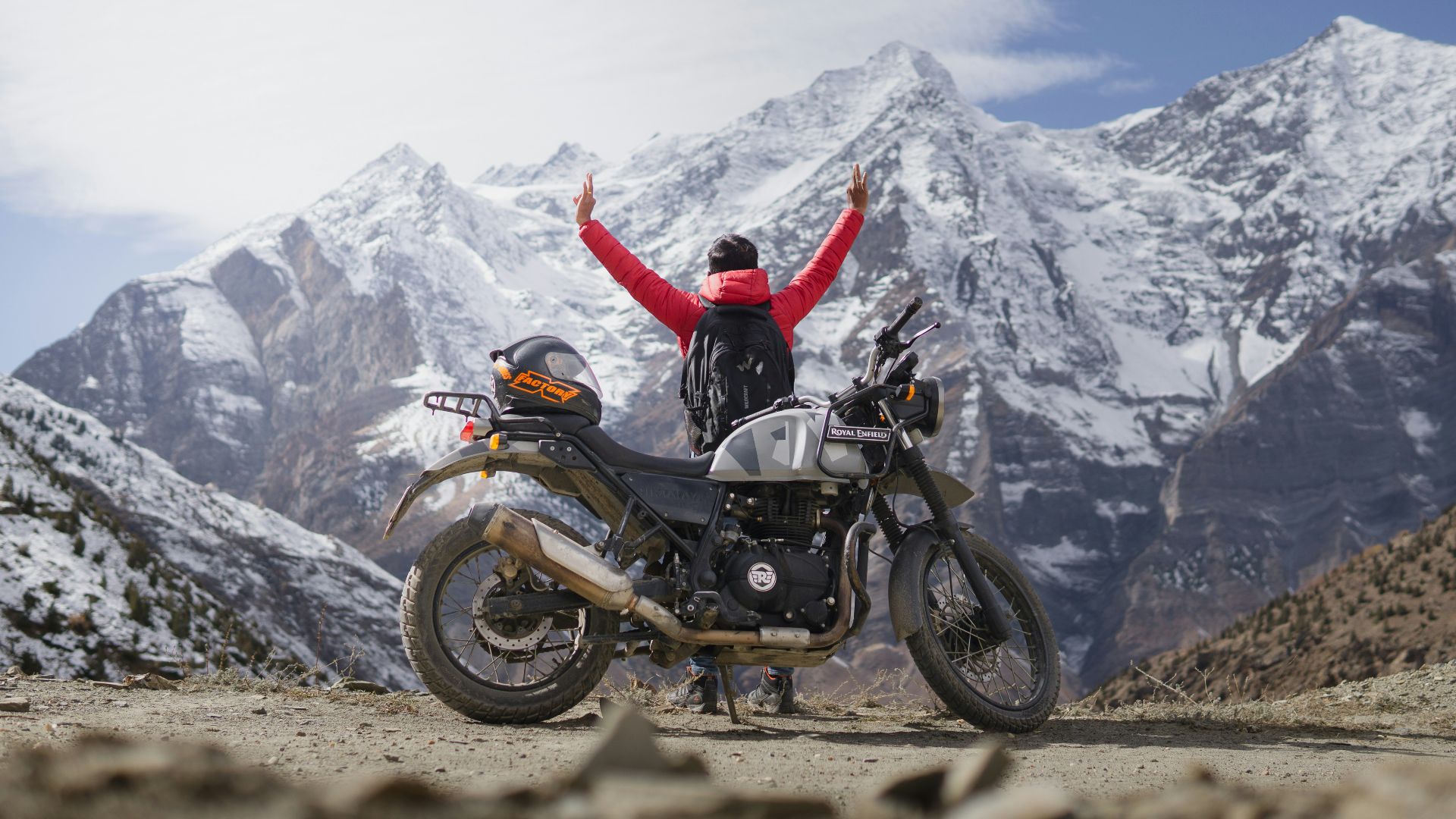 a person standing next to a motorcycle on a dirt road