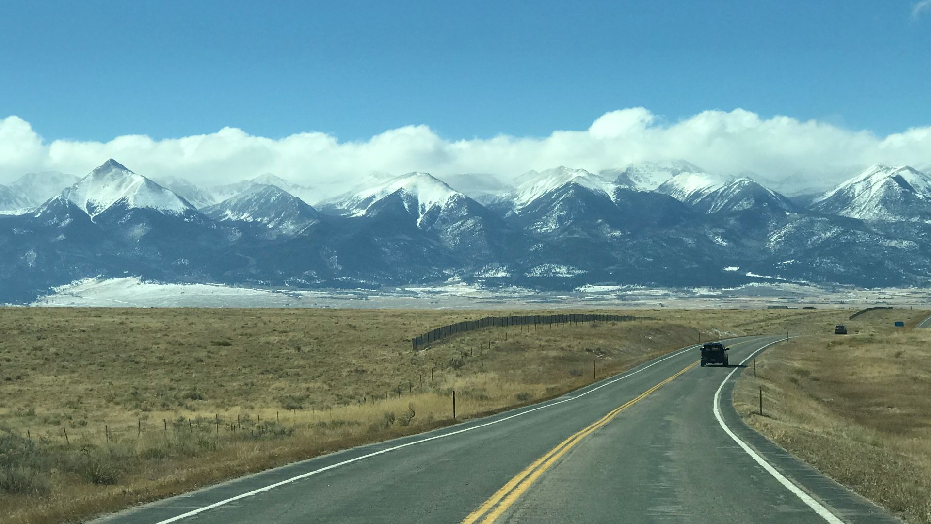 A car driving down a road with mountains in the background