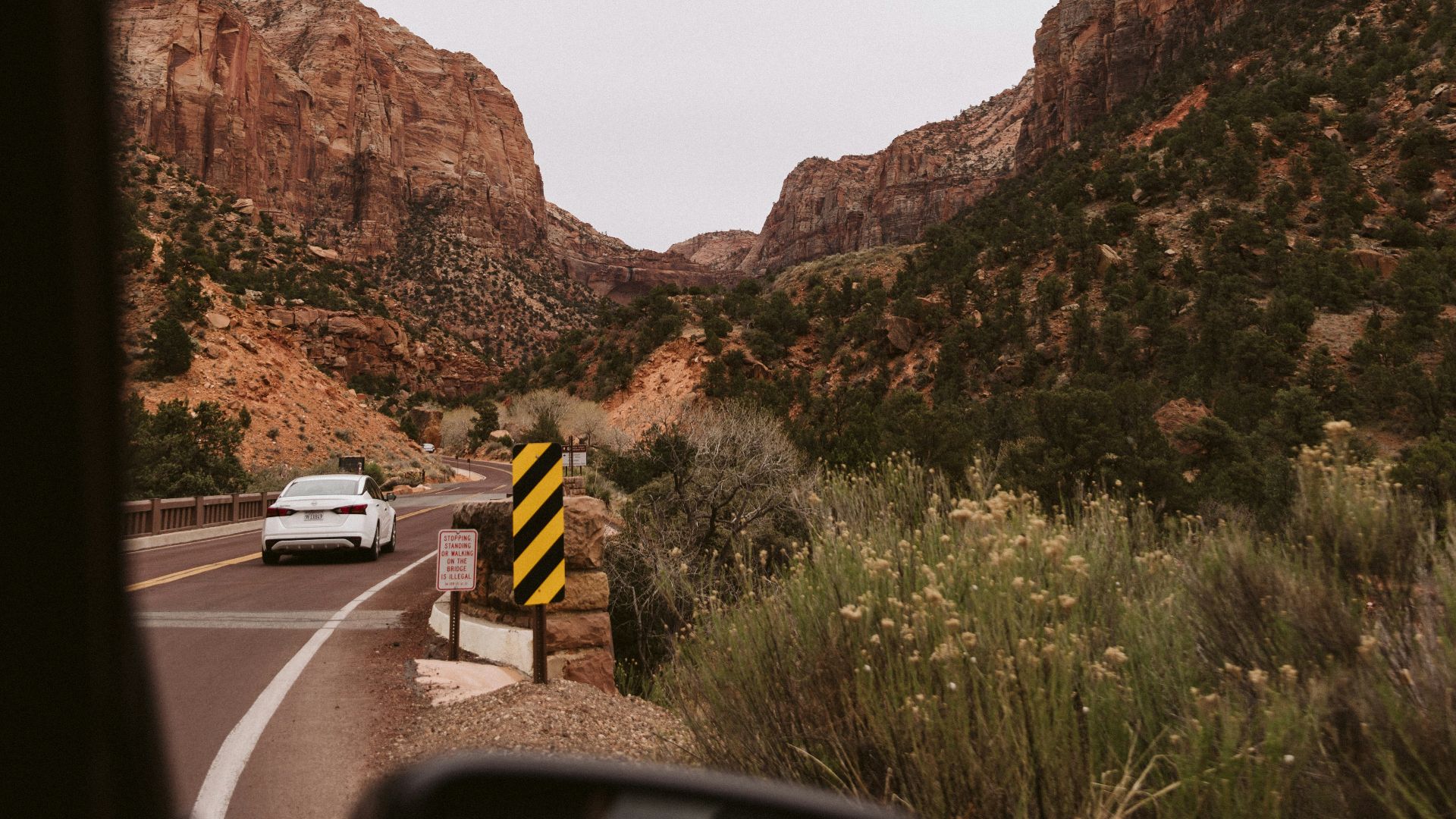 a car driving down a road next to a mountain