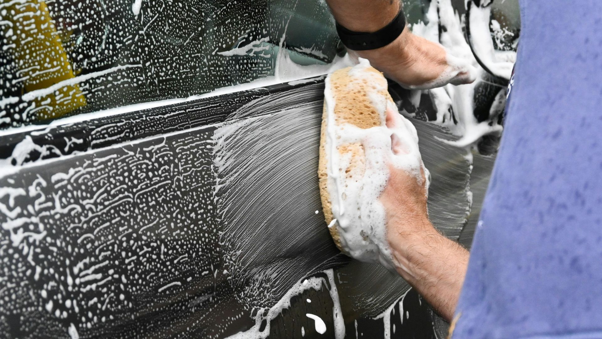 a man washing a car with a sponge