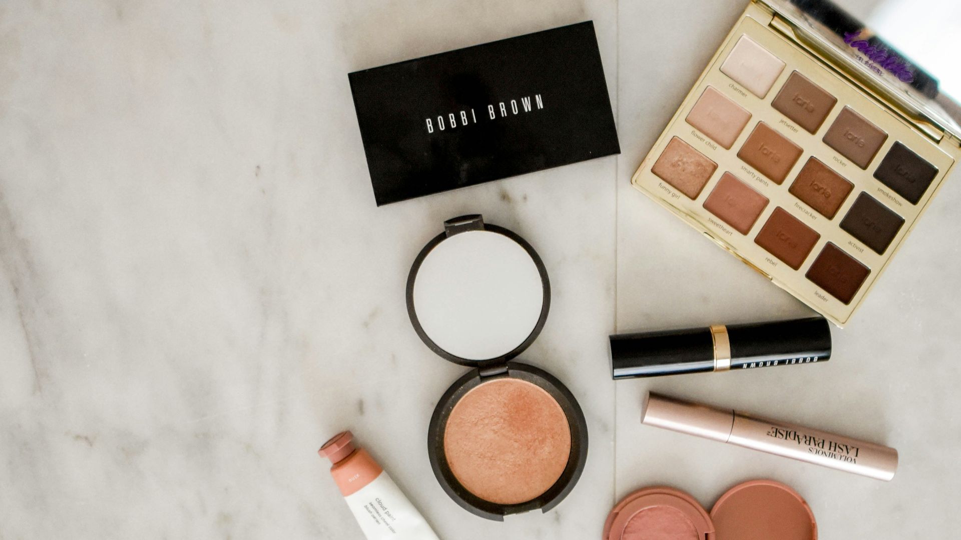 photo of assorted makeup products on gray surface