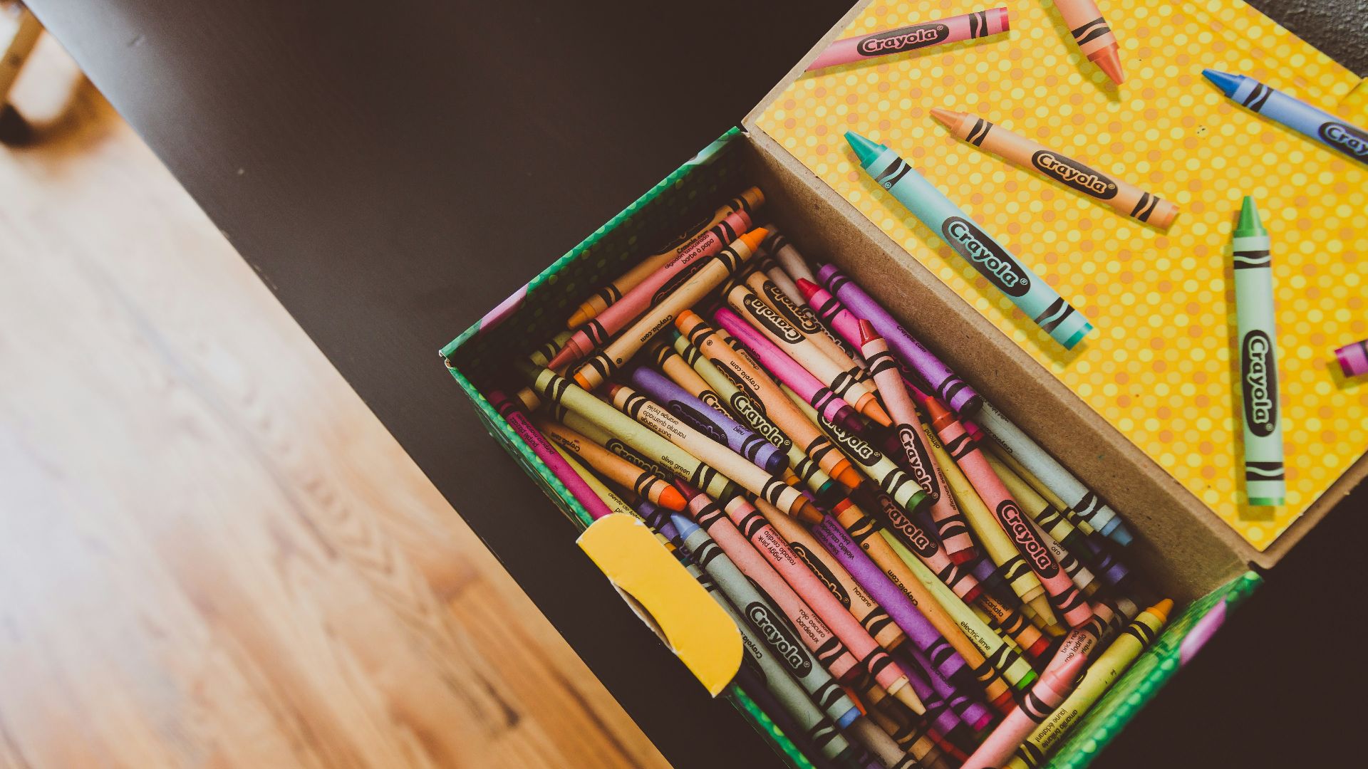 assorted crayons in box on wooden table