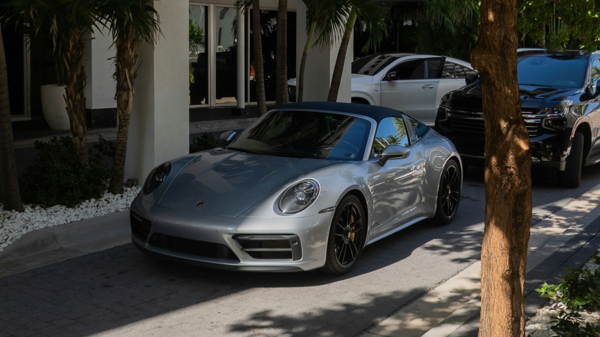 A silver porsche car is parked outside.