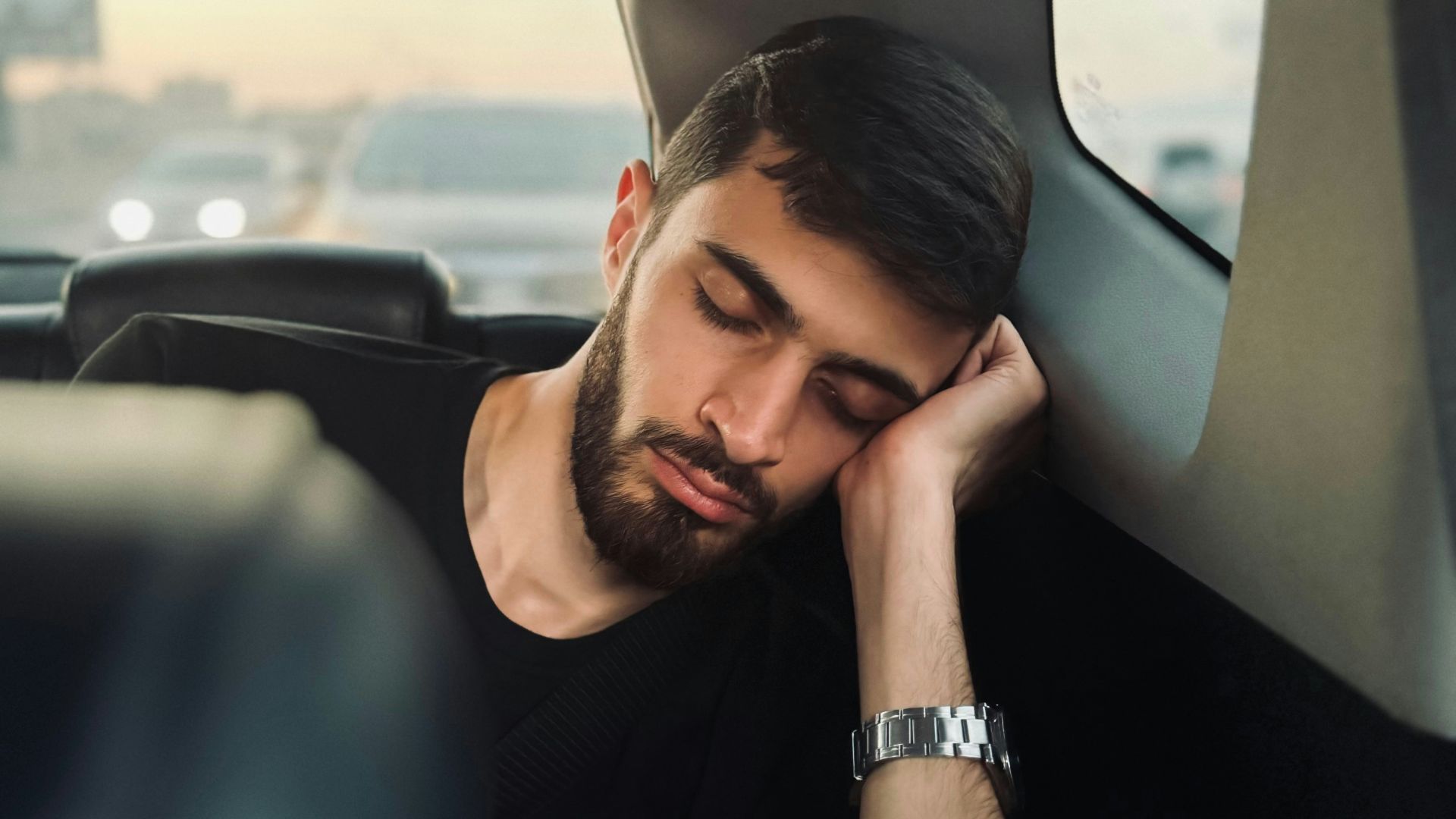 A man sitting in the back seat of a car