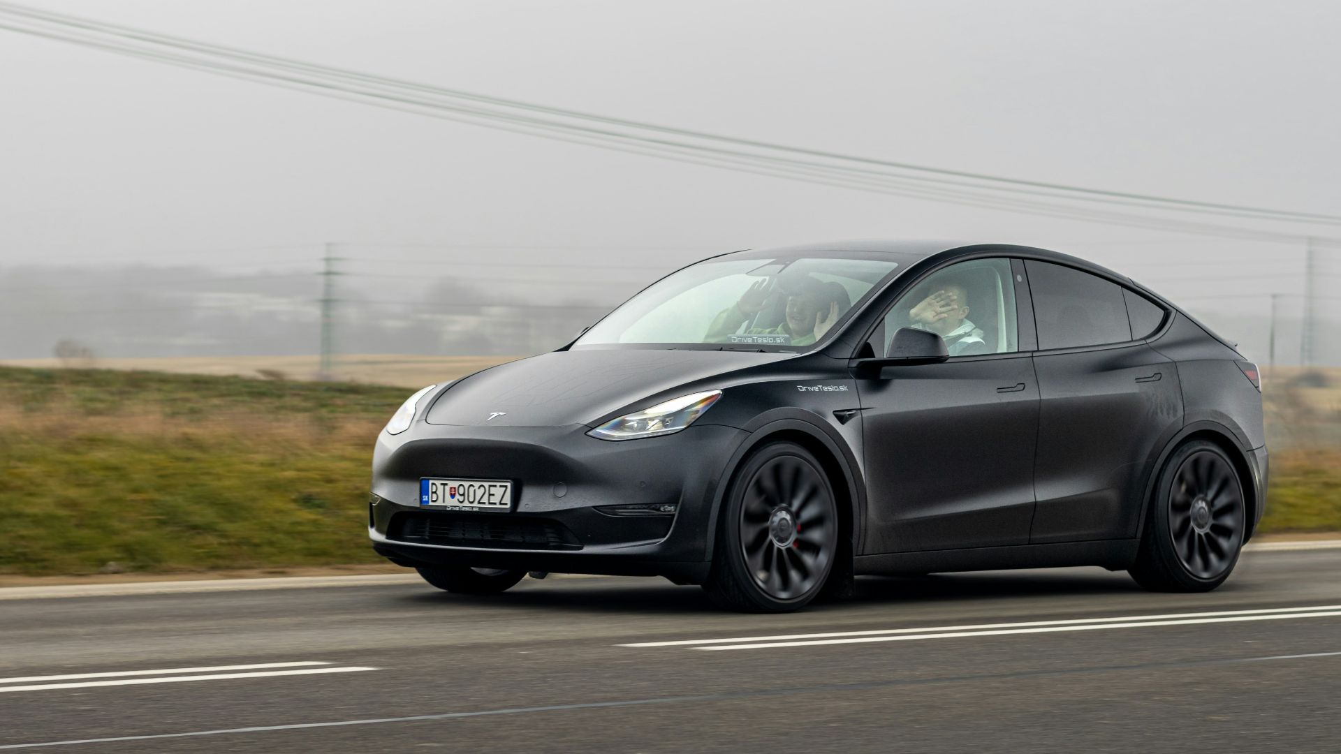 a black tesla car driving down the road