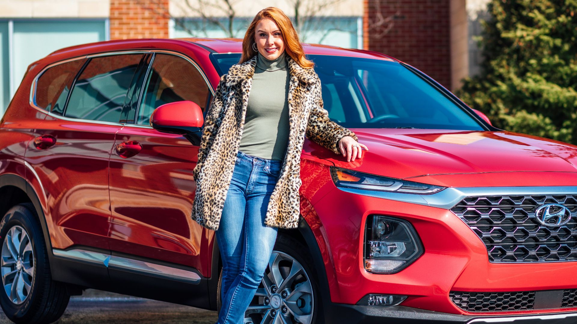 woman in white and black scarf and blue denim jeans standing beside red mercedes benz car