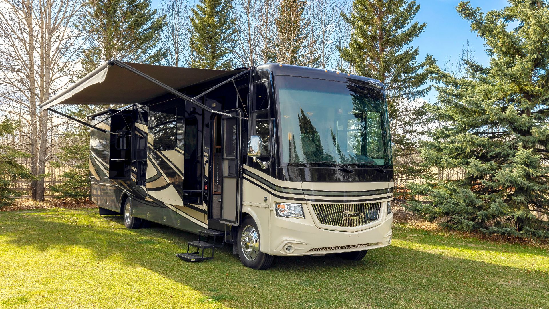 a motor home parked in the grass near some trees