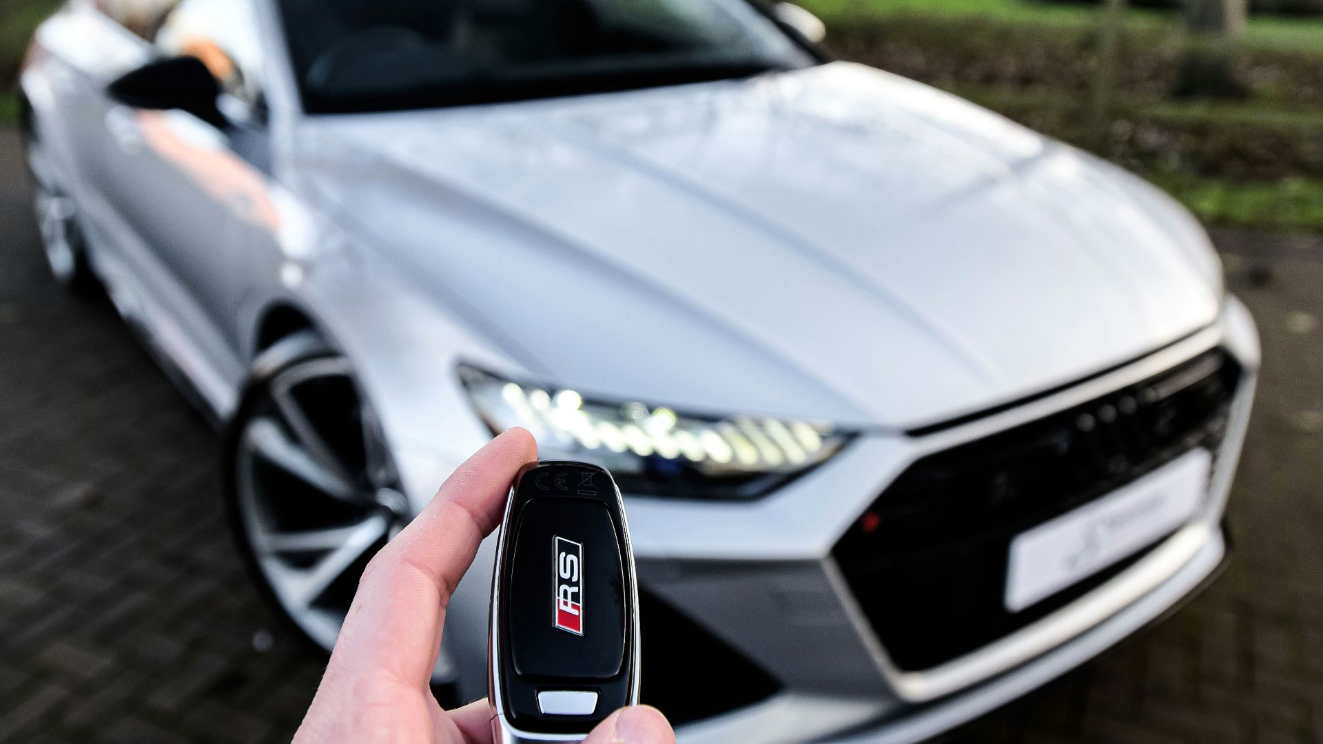 a person holding a car key in front of a silver car