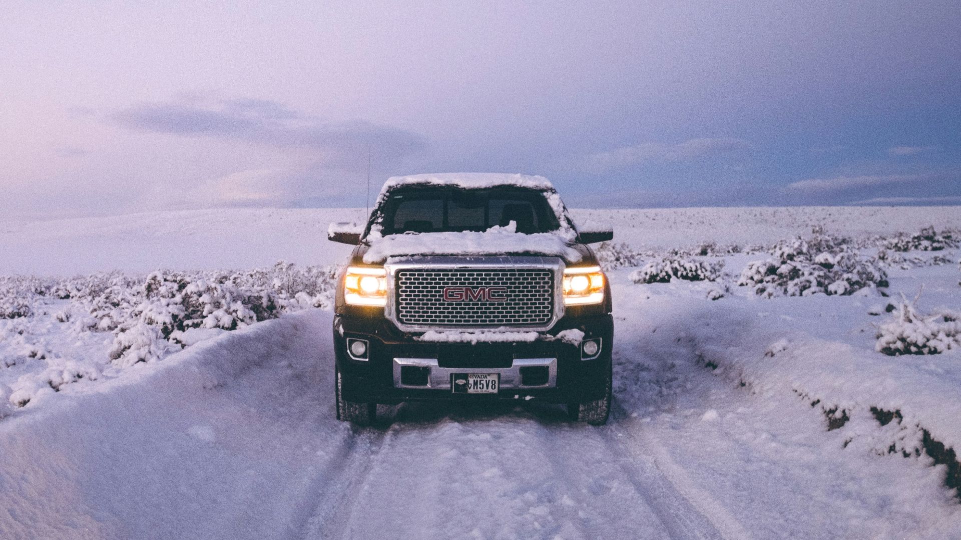 black GMC Sierra Denali on snow covered road