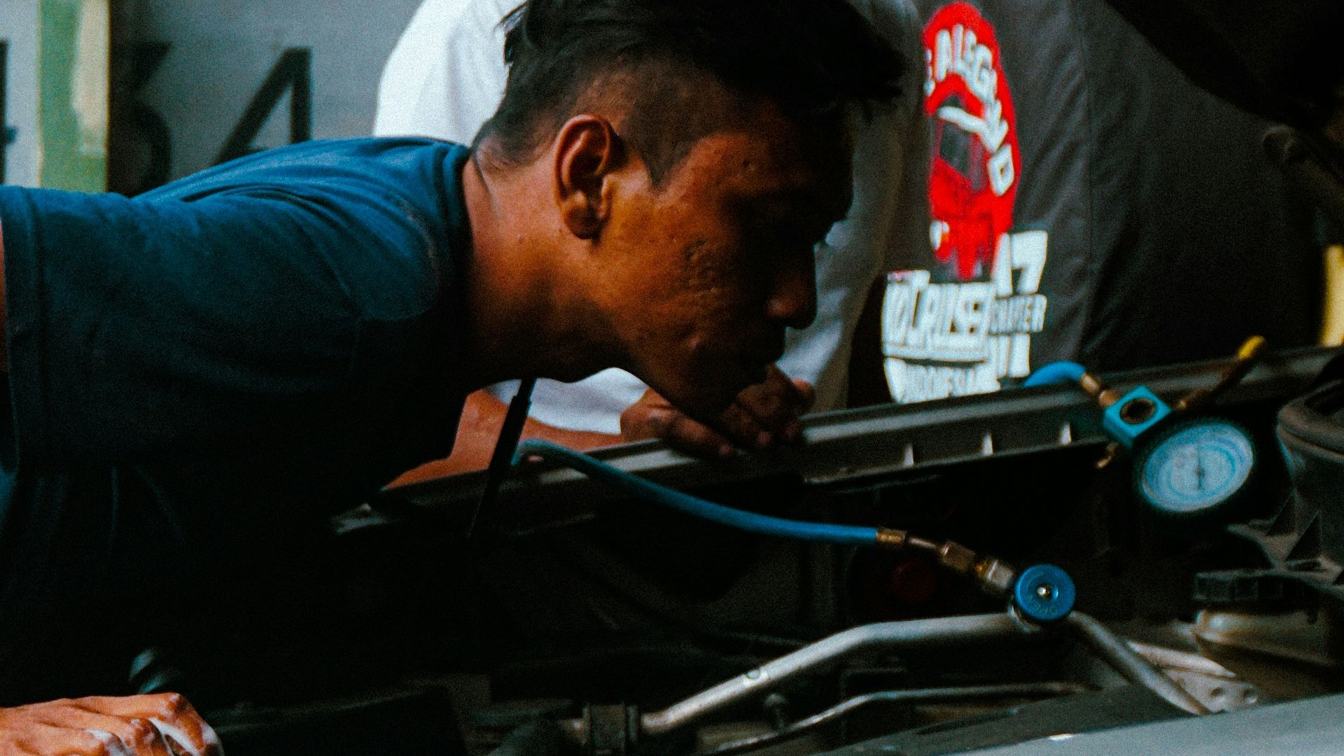 two men working on a car engine in a garage