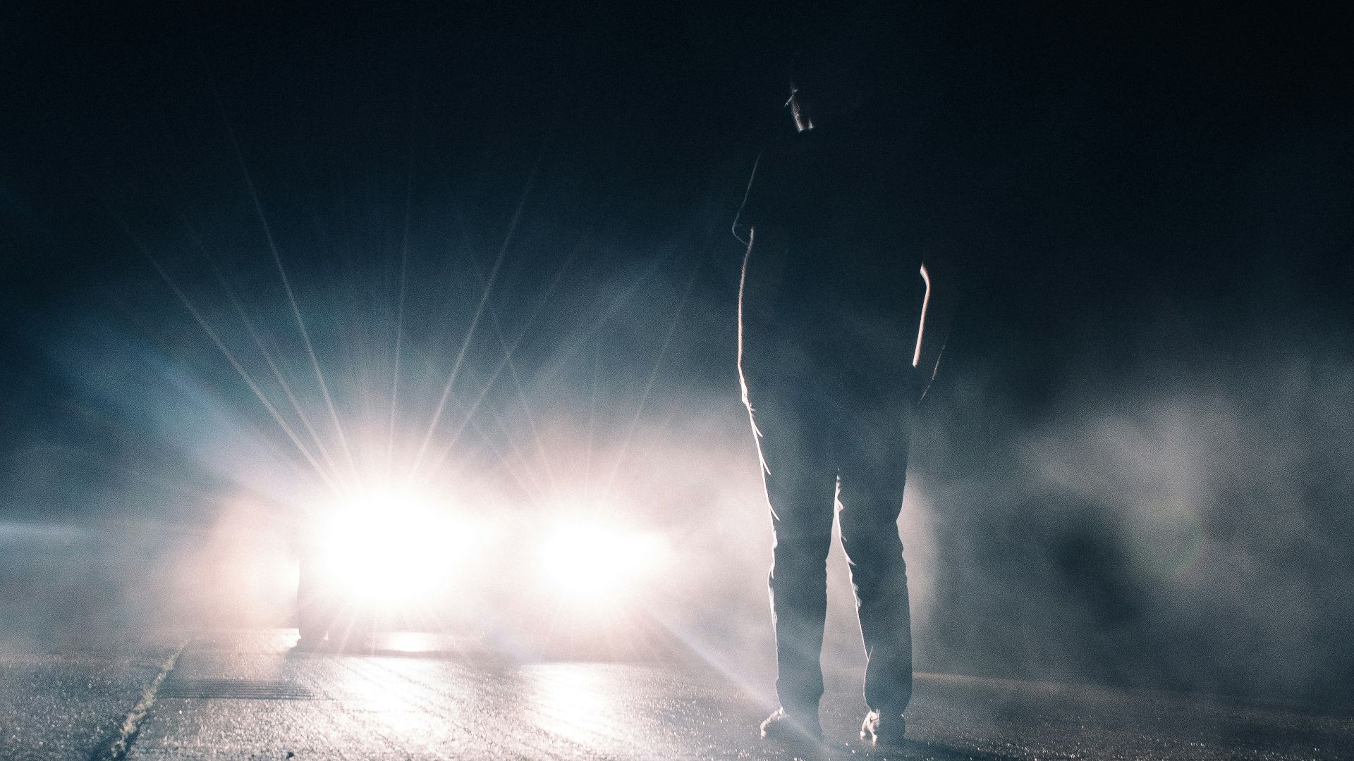 man standing in front of lighted car