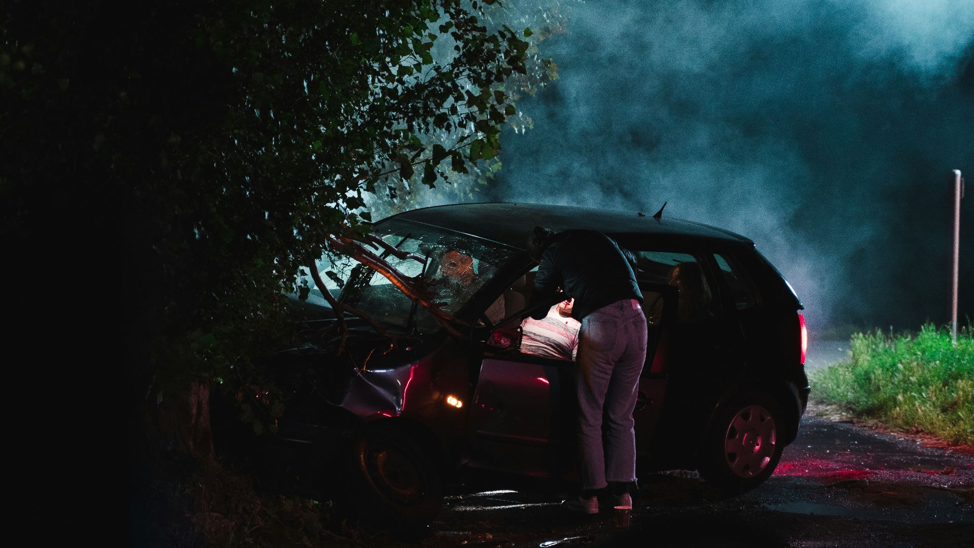 a person standing next to a car with smoke coming out of it