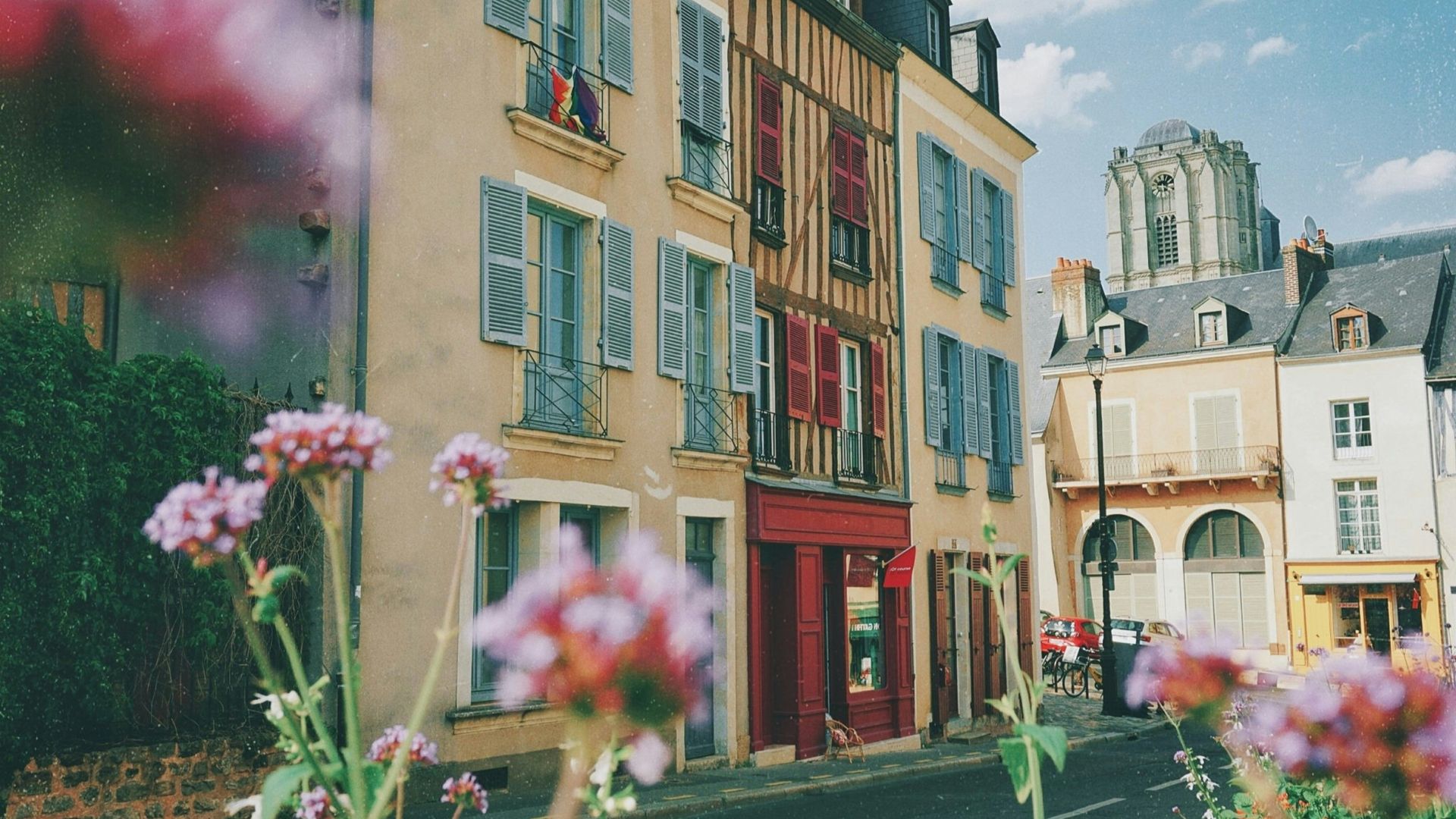a street with flowers and buildings in the background