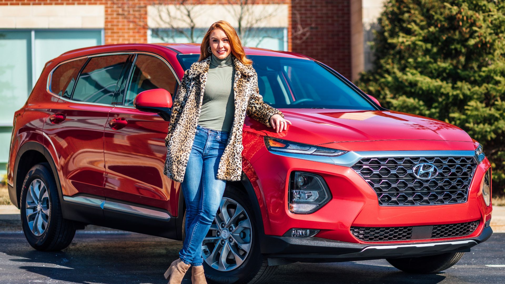 woman in white and black scarf and blue denim jeans standing beside red mercedes benz car