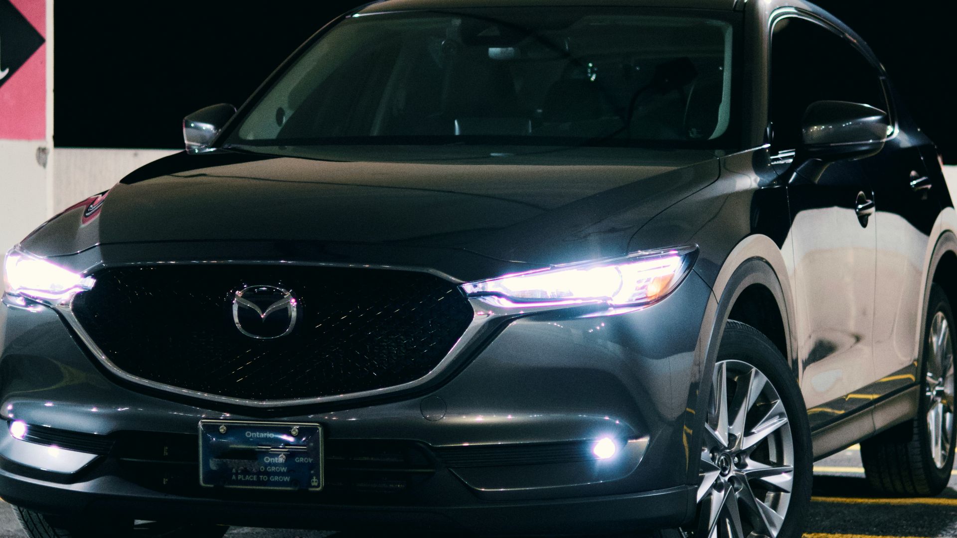 A black mazda suv is parked at night.