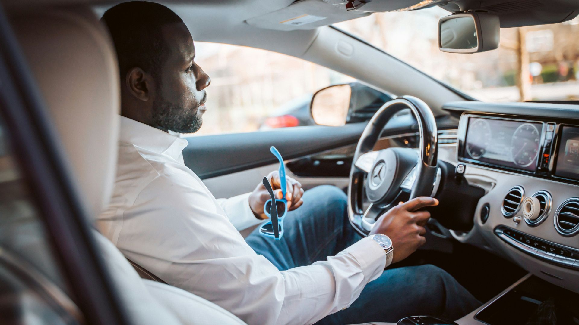 man in white dress shirt driving car during daytime