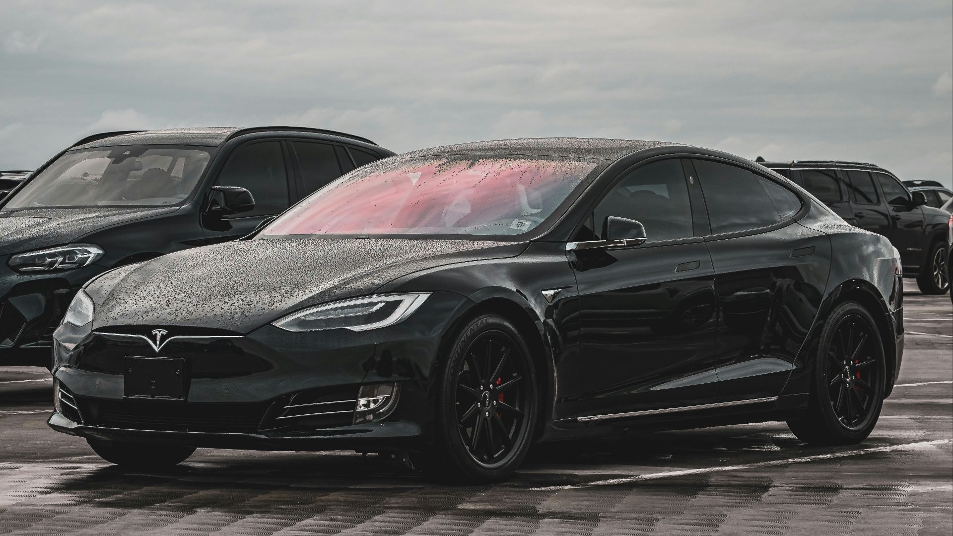 a black tesla parked in a parking lot
