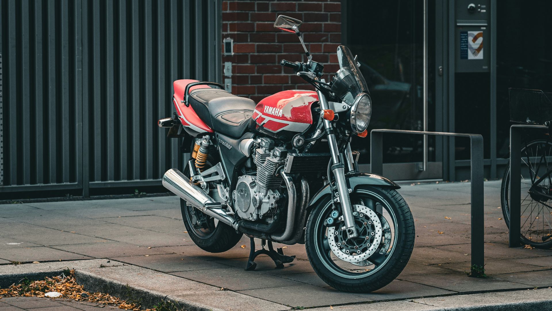 Red motorcycle parked on a city sidewalk.