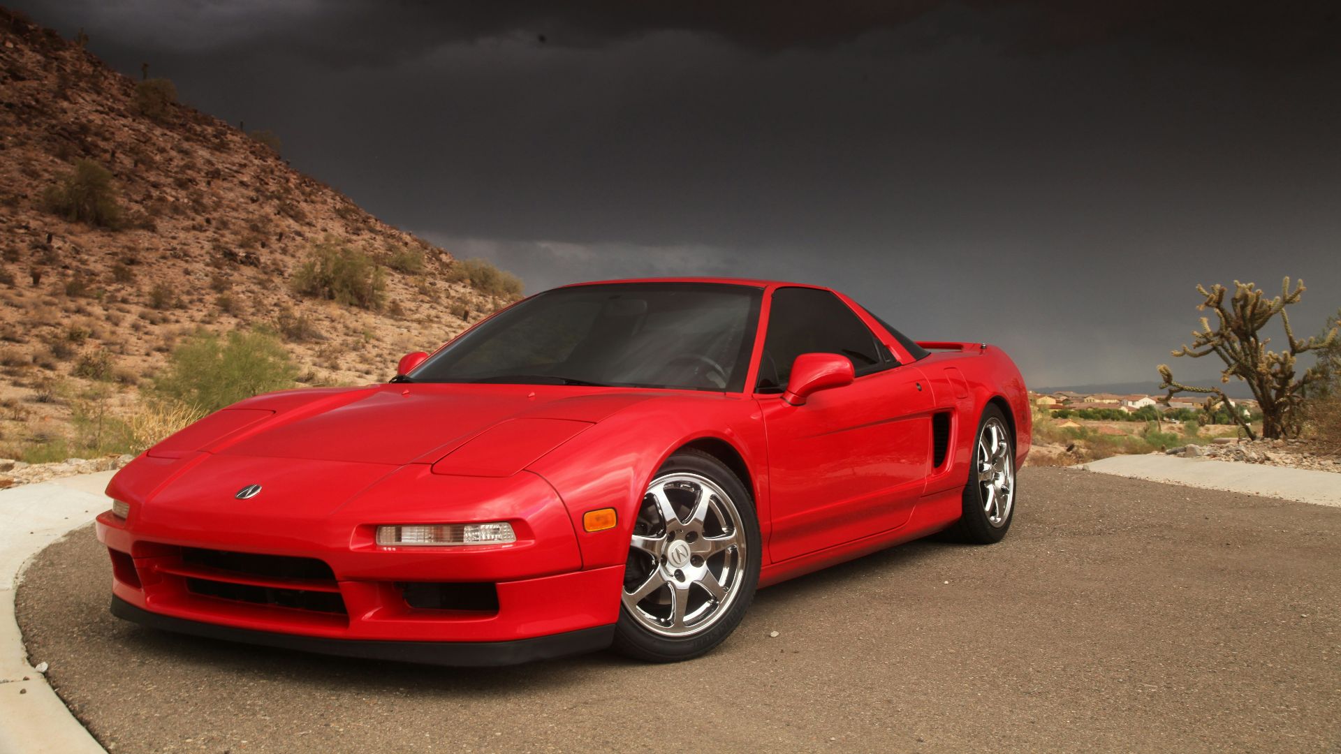 a red sports car parked on a road with hills in the background
