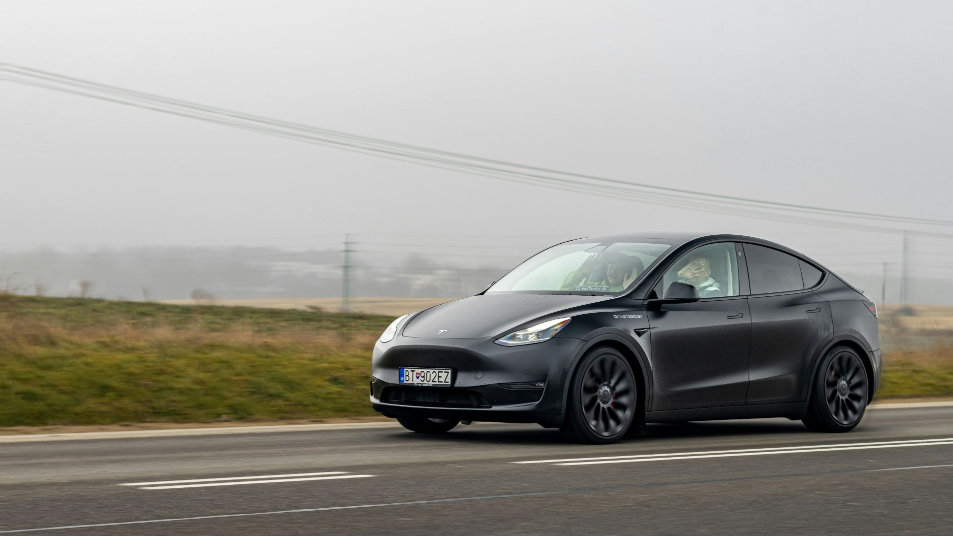 a black tesla car driving down the road