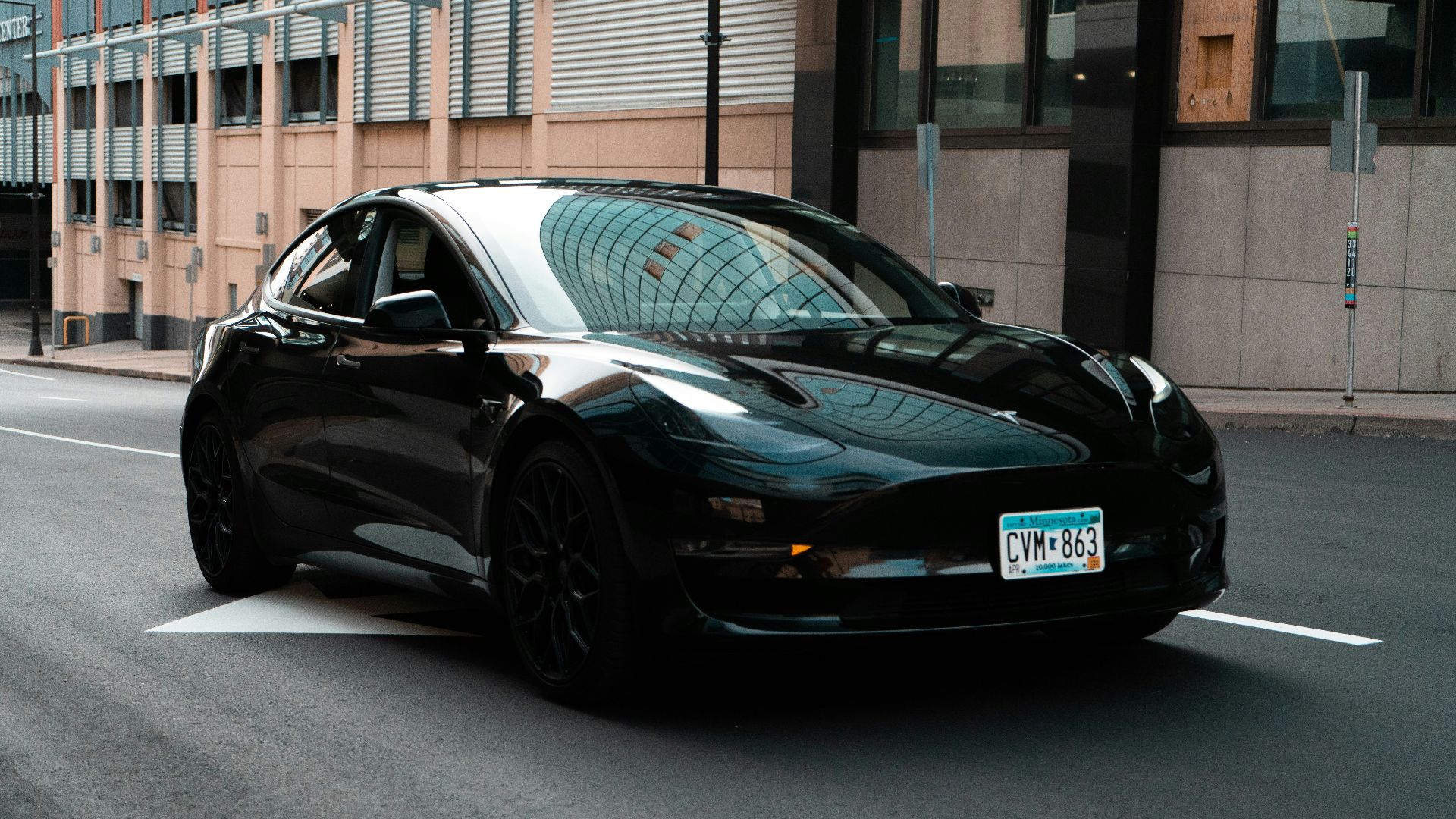 a black car driving down a street next to a tall building