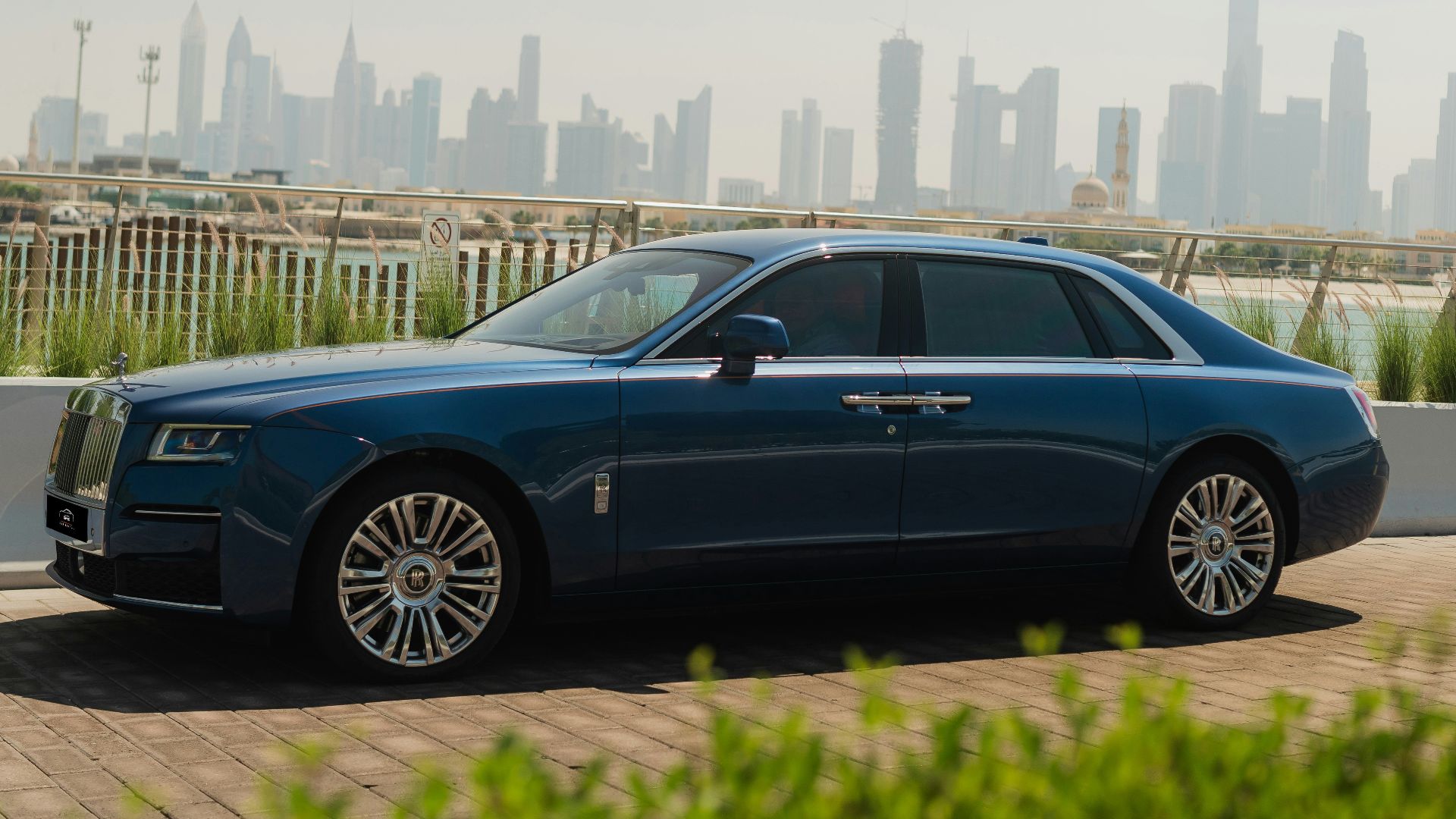 A blue rolls royce parked in front of a city