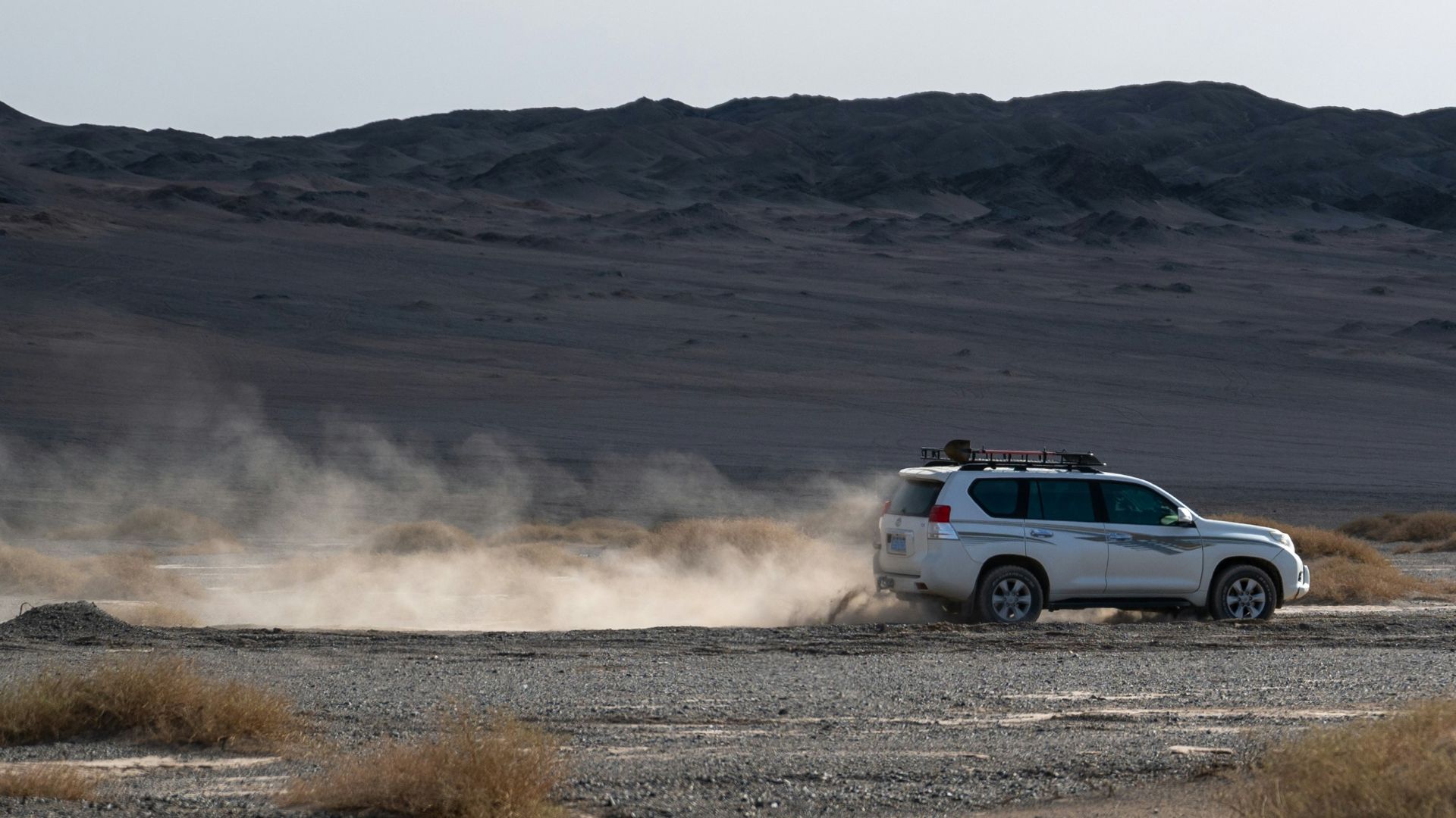 A white truck driving down a desert road