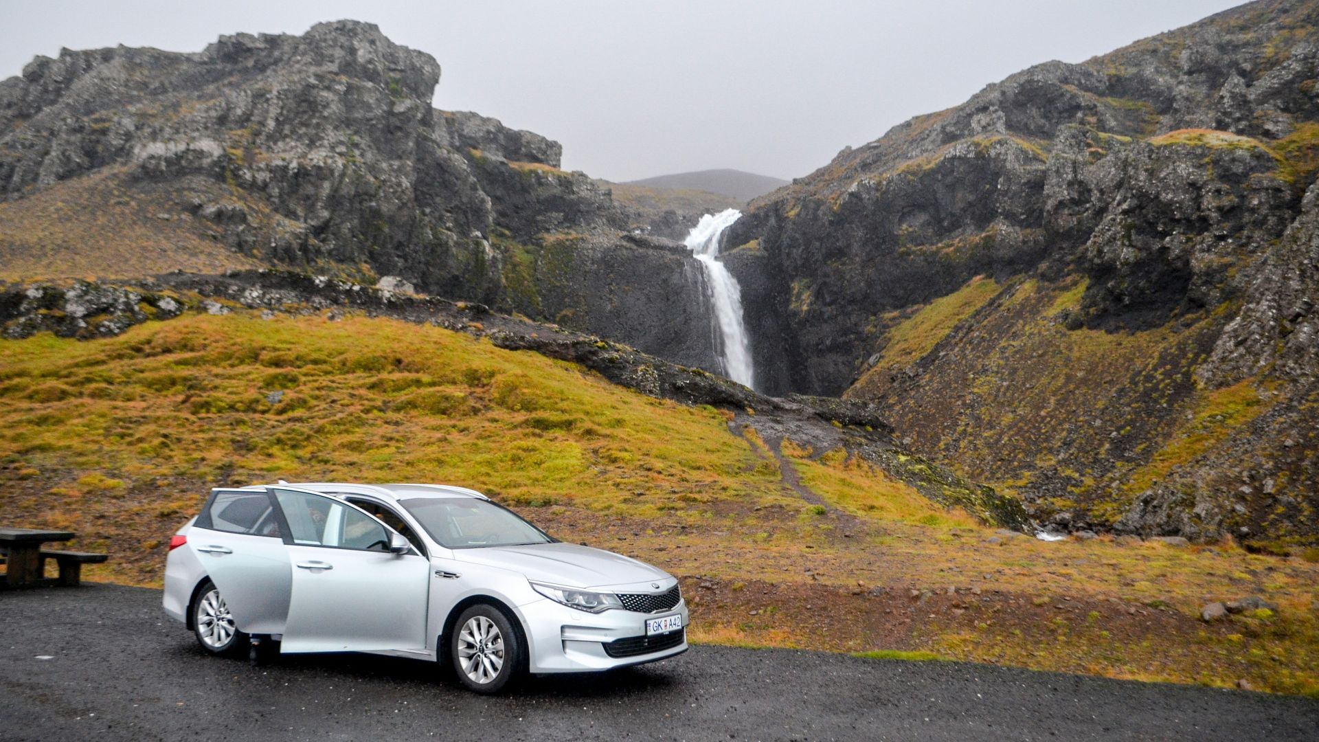 a white car parked in front of a waterfall