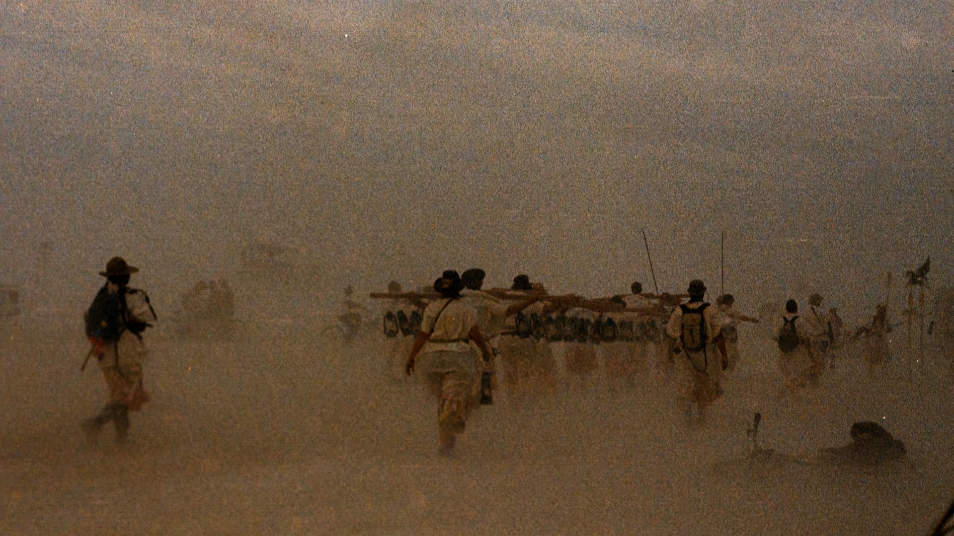 A group of people walking across a sandy beach
