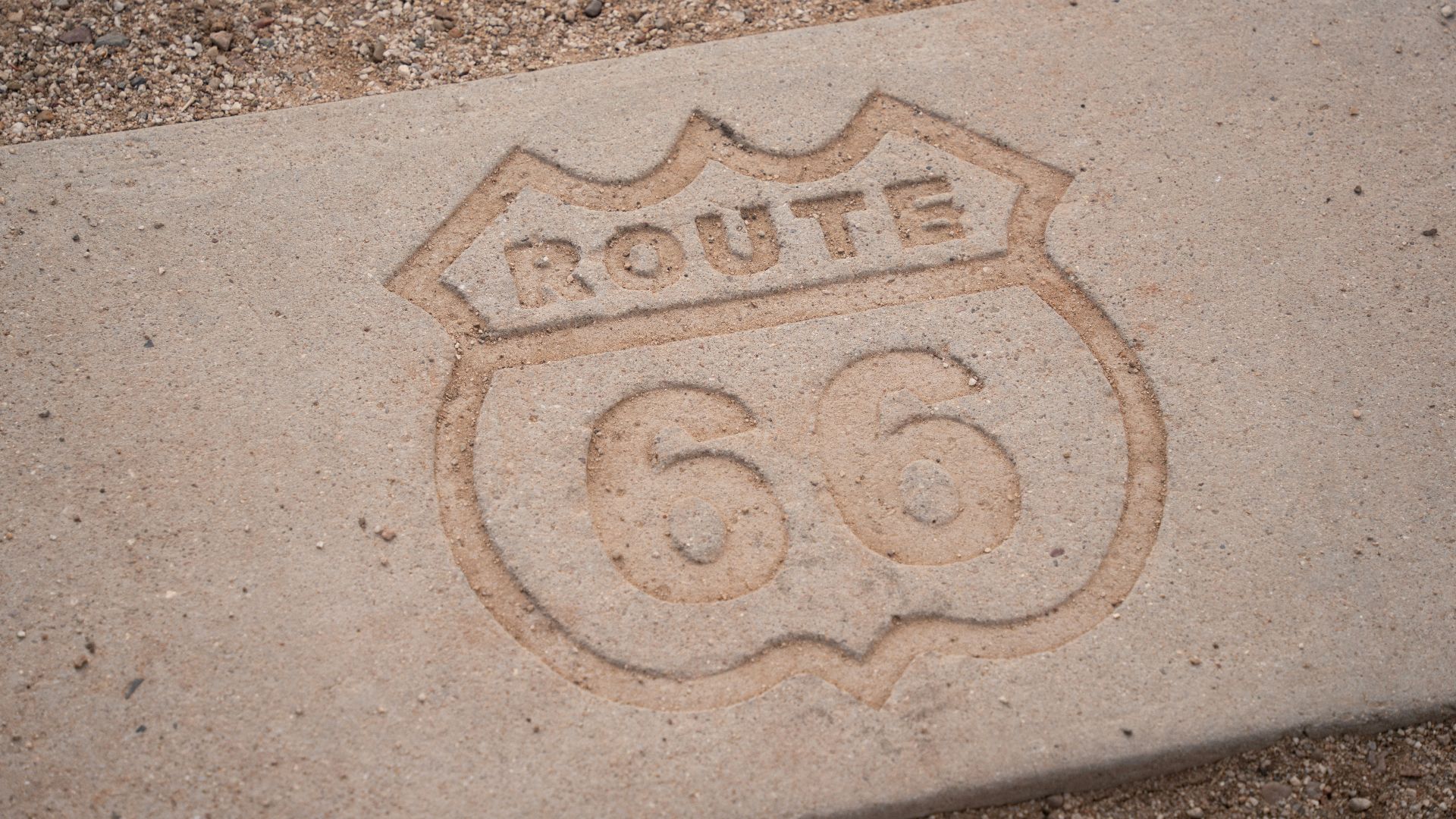 a route 66 sign carved into a sidewalk