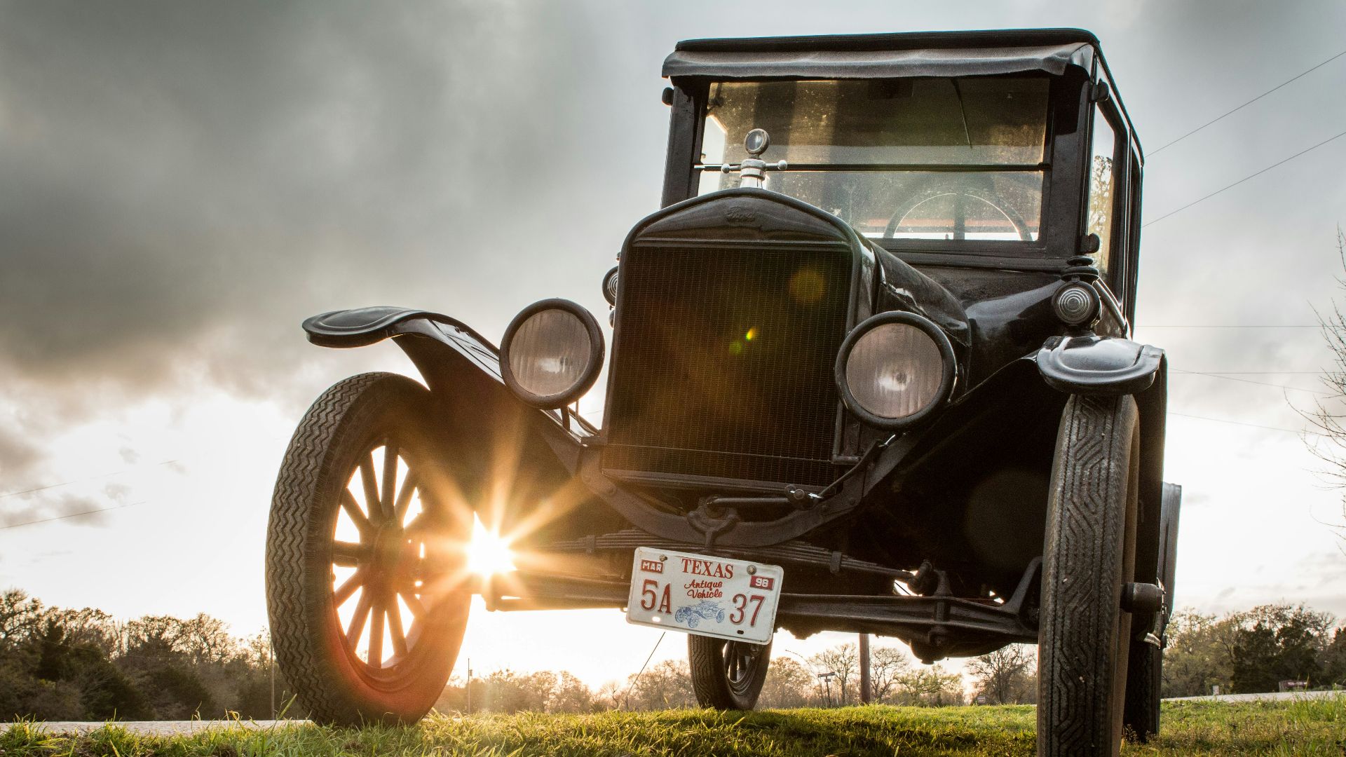 vintage black car on green grass field under cloudy sky during daytime